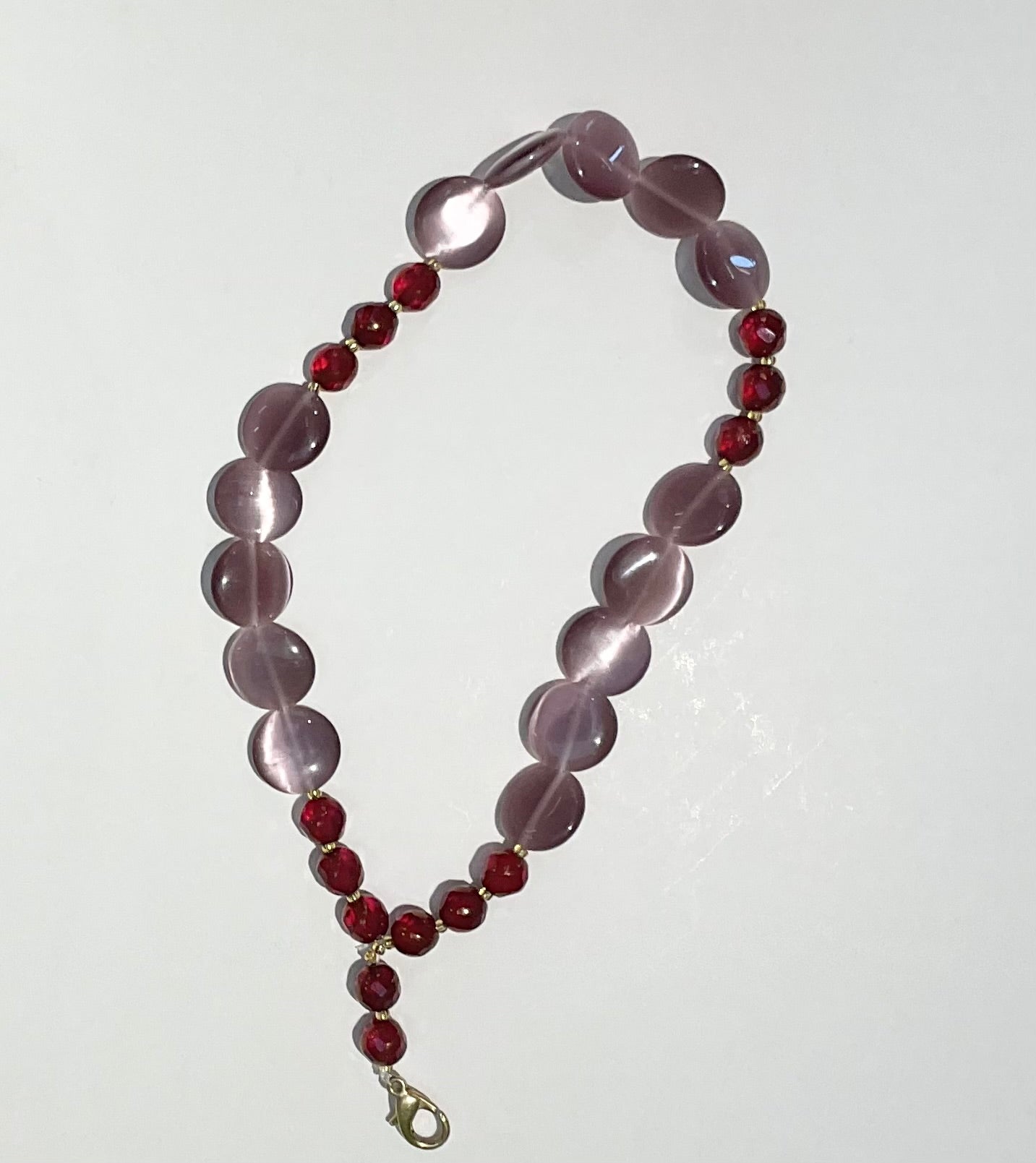 Beaded keychain with light purple and red beads on a white background