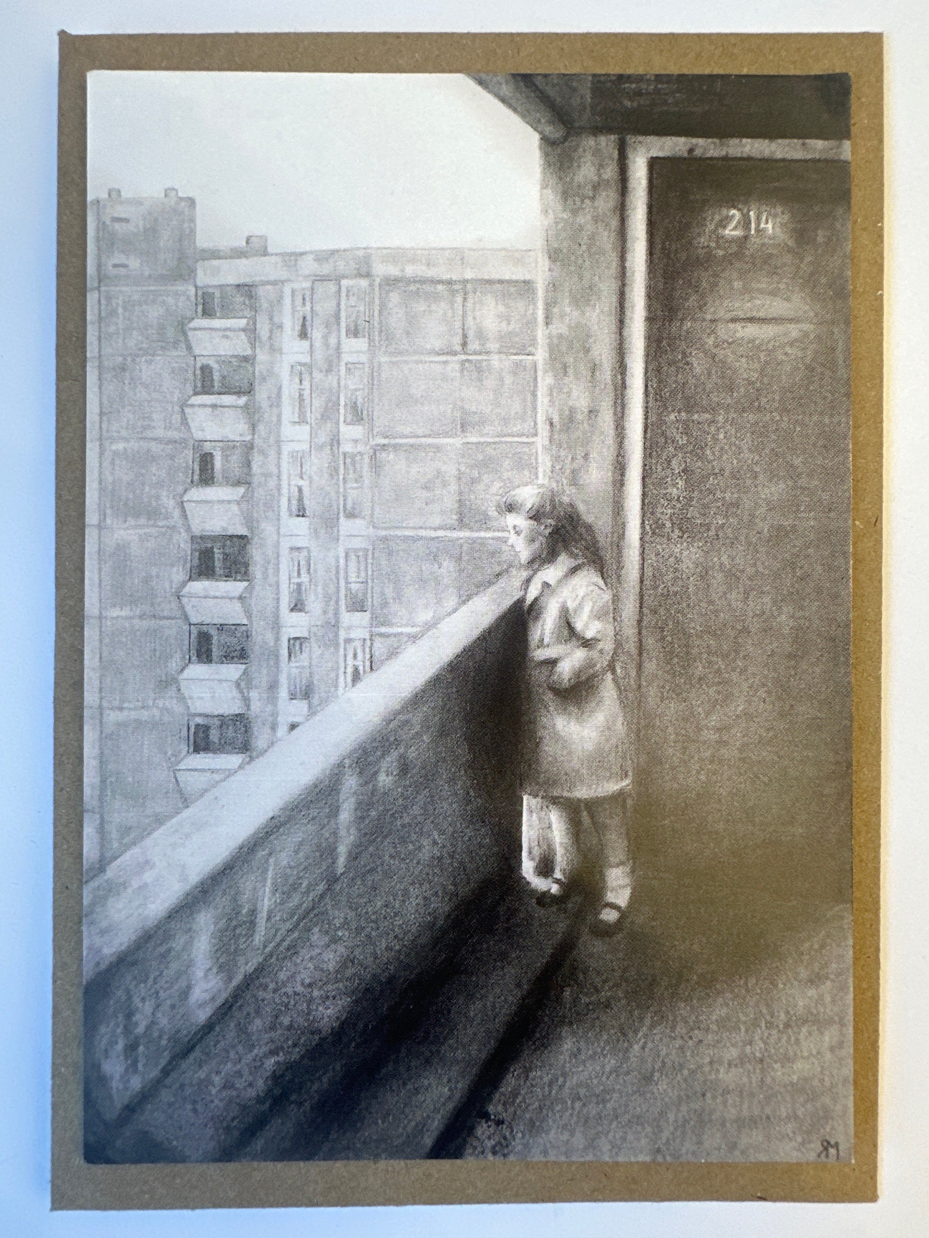 Postcard featuring a black and white drawing of a girl standing on a balcony, with Ballymun Flats n the background