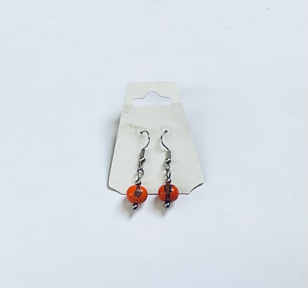 Pair of earrings with orange beads on a white background