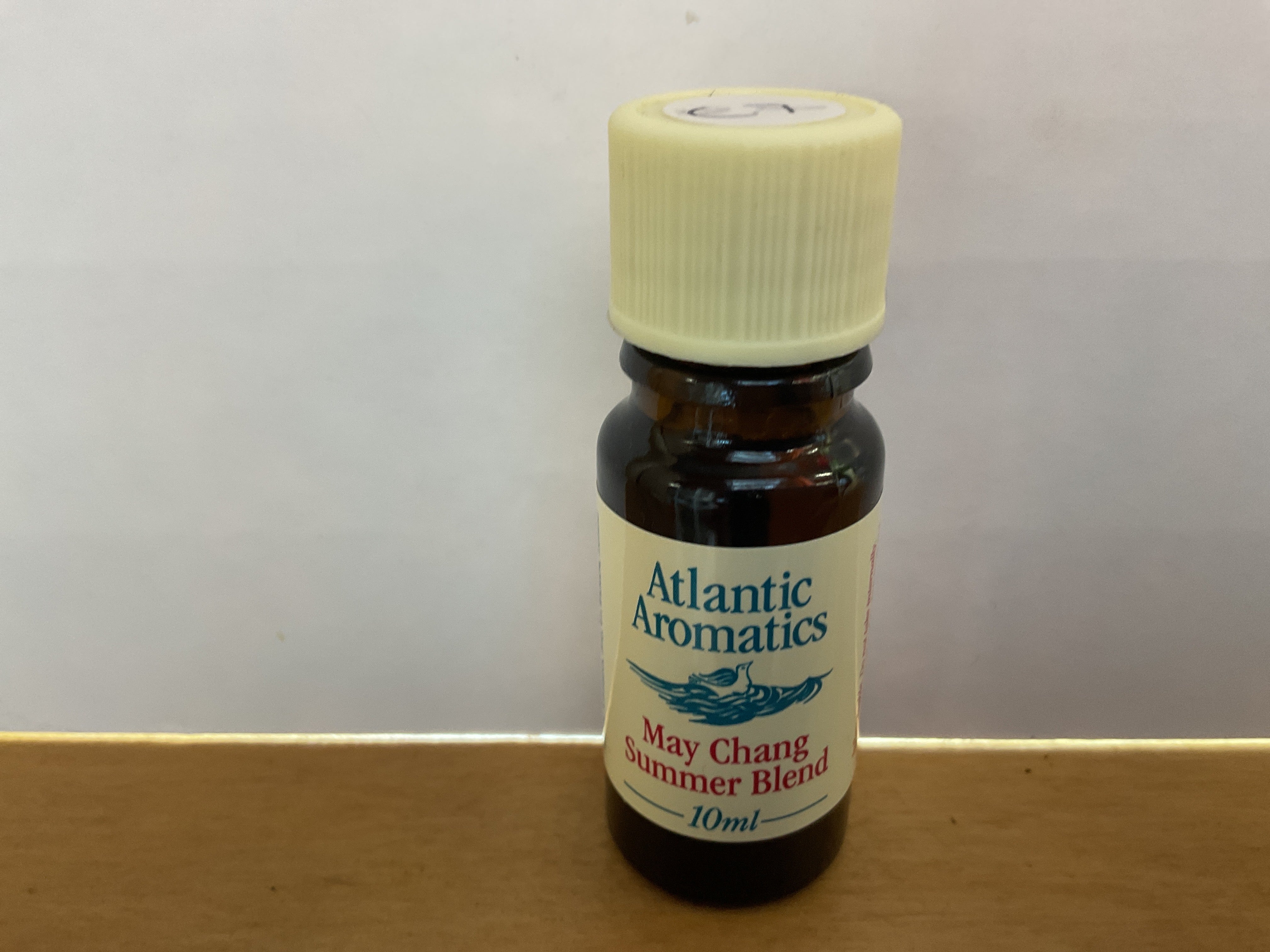 Bottle of Atlantic Aromatics May Chang Summer Blend essential oil on a wooden surface with a white background