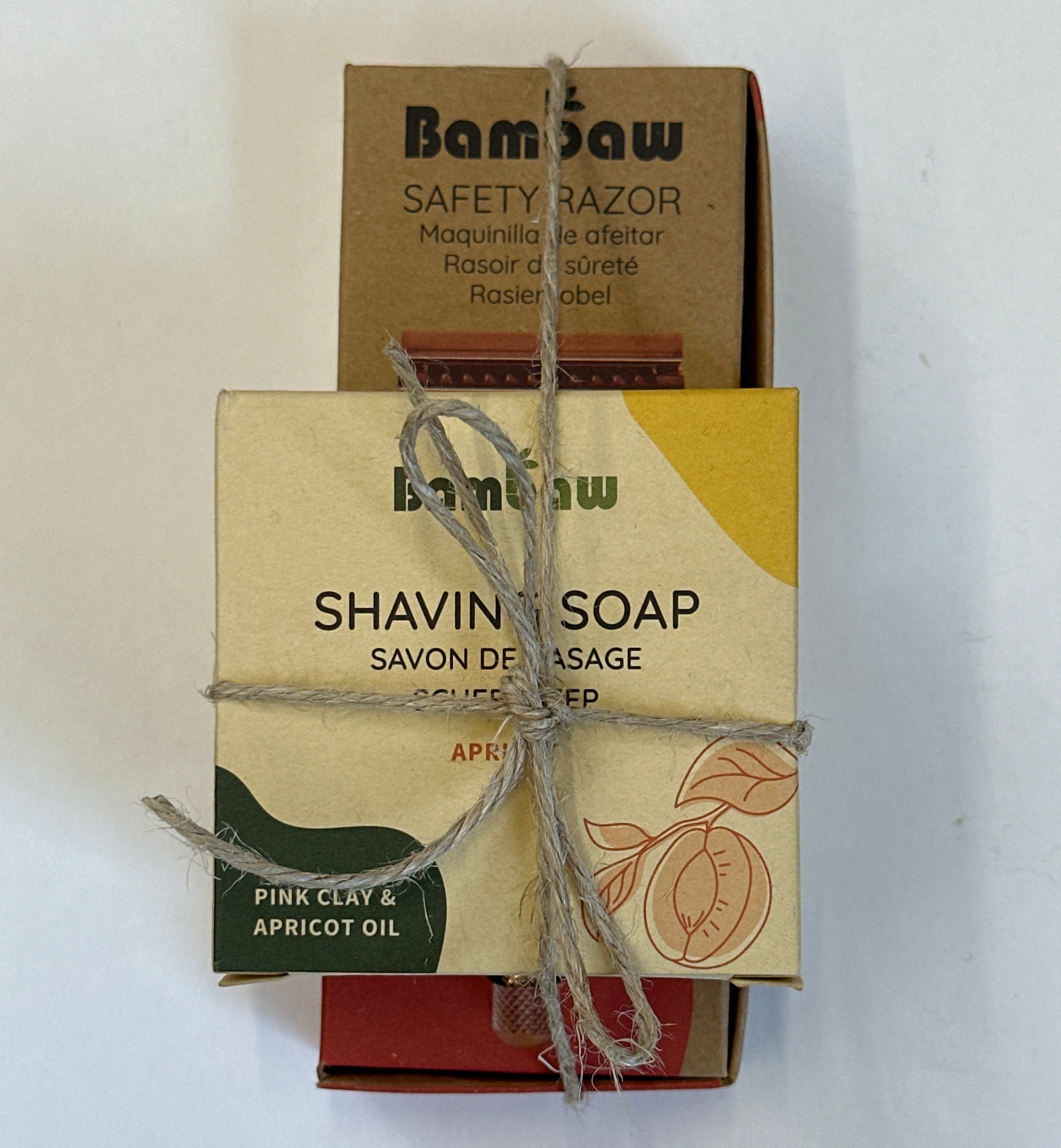 A boxed shaving soap product wrapped in twine, with the front label reading 'bamboo SHAVING SOAP' and 'PINK CYDDE & APRICOT OIL,' placed over a brown cardboard razor box on a white background.