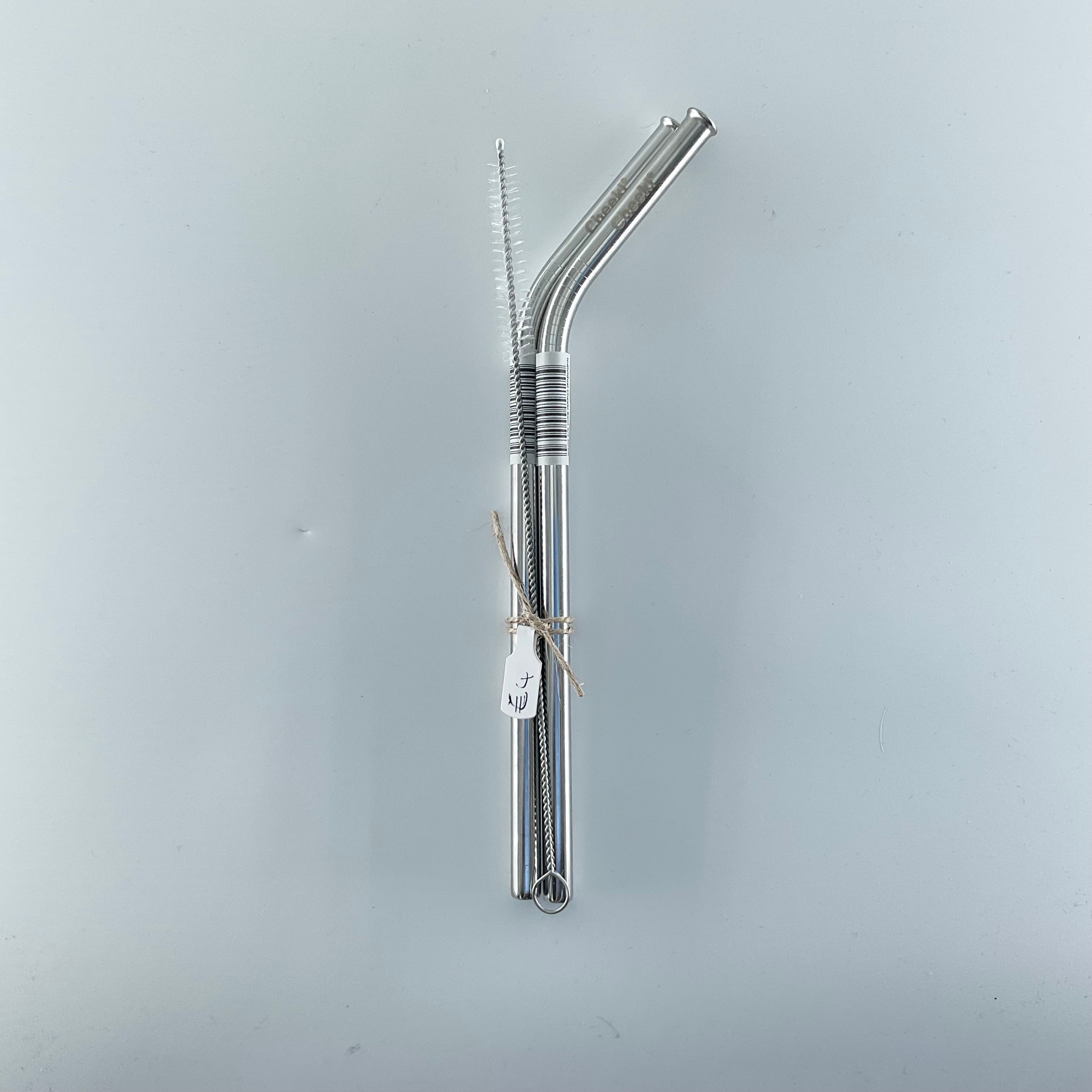 Two metal straws with a cleaning brush on a light gray background