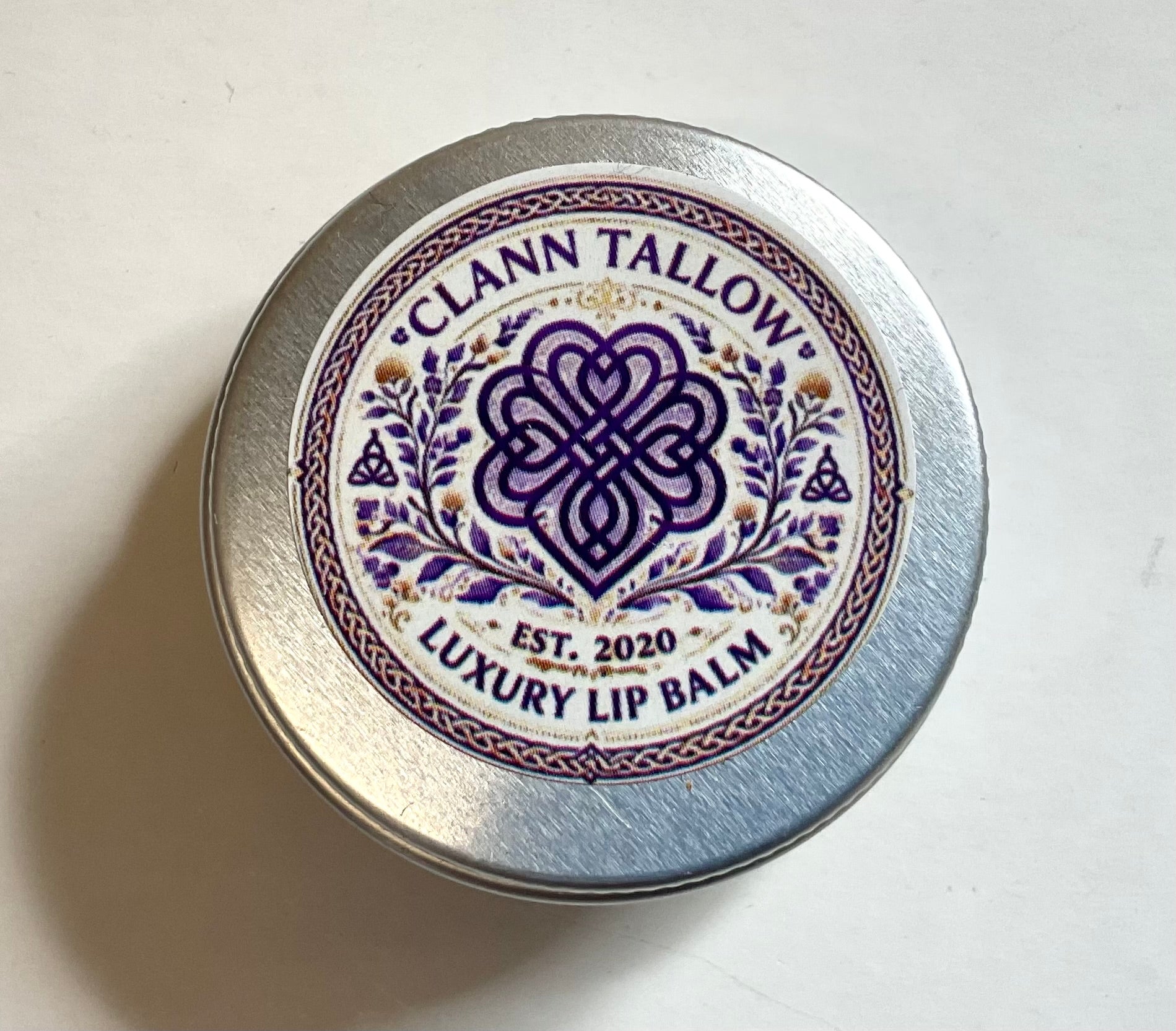 Clann Tallow luxury lip balm container with decorative label on a white background