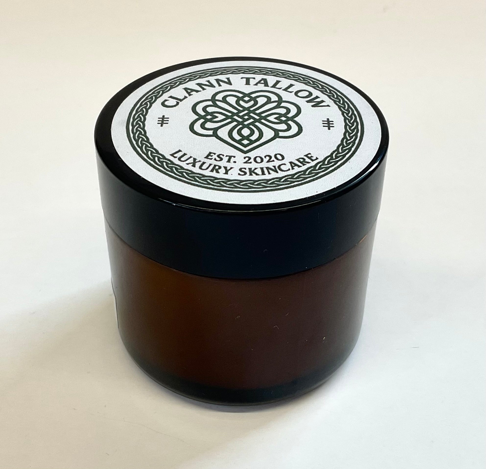 Brownglass  jar with black lid featuring 'Clann Tallow Luxury Skincare' on a white background