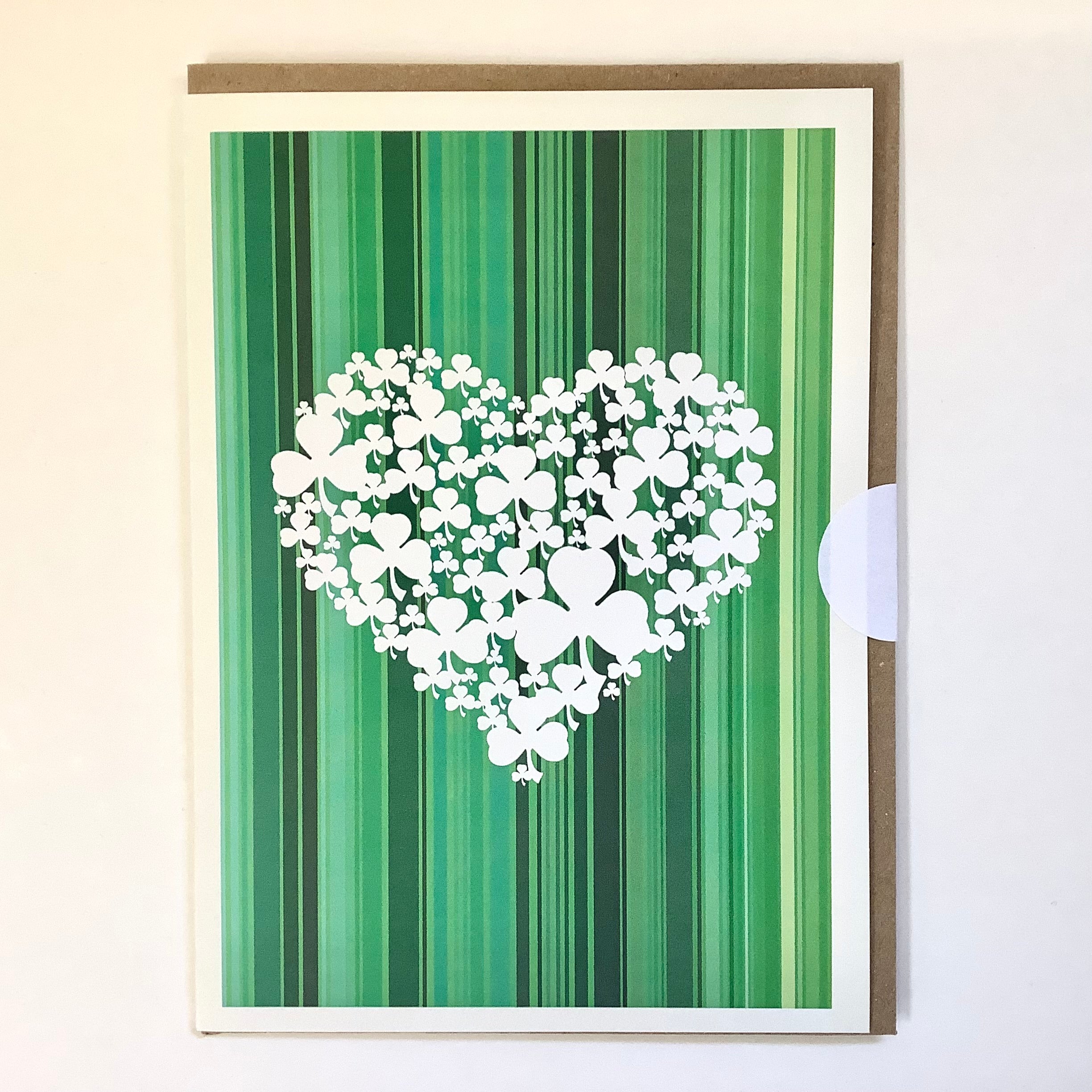 Card with a heart made of shamrock shapes on a green striped background