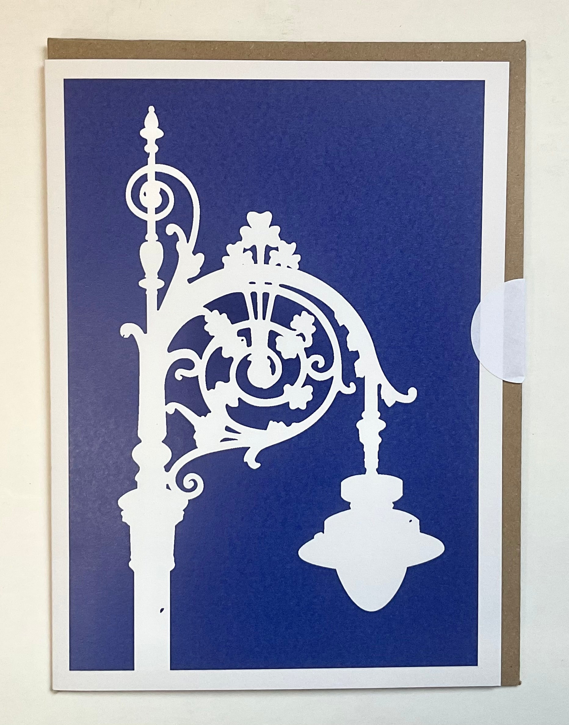Decorative card with white metalwork design on a blue background