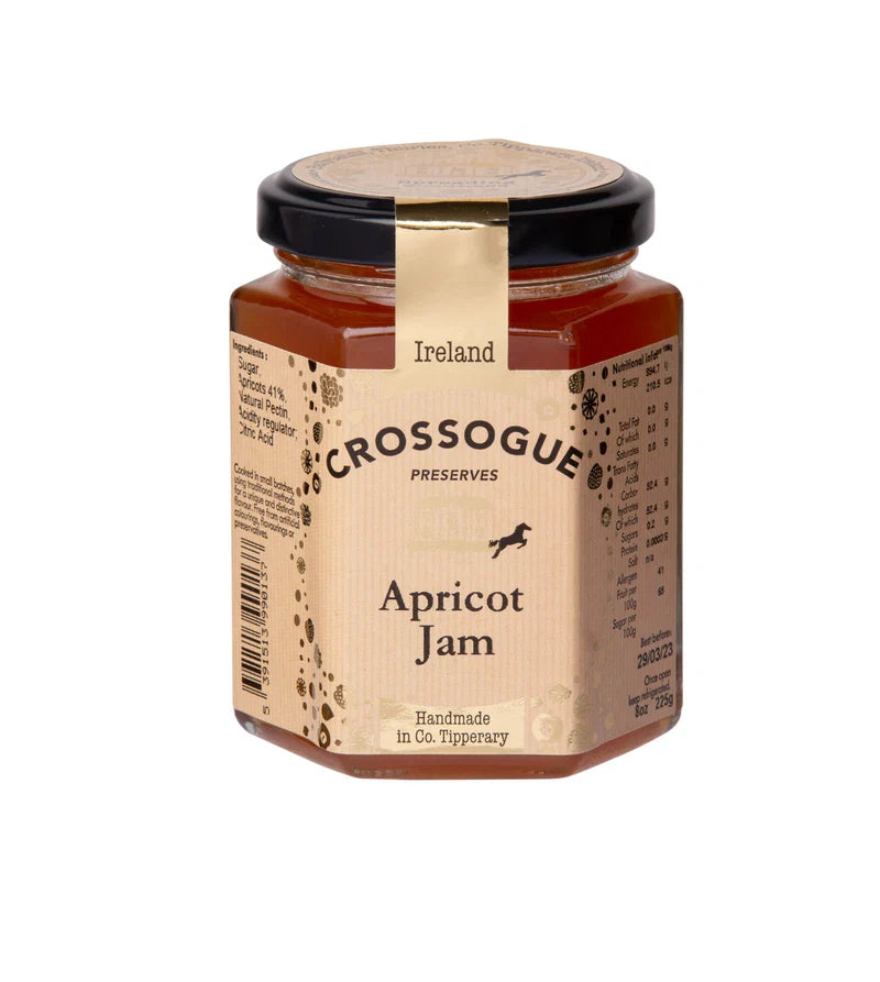 A glass jar of Crossogue Preserves Apricot Jam with a beige label and black lid, set against a plain white background.