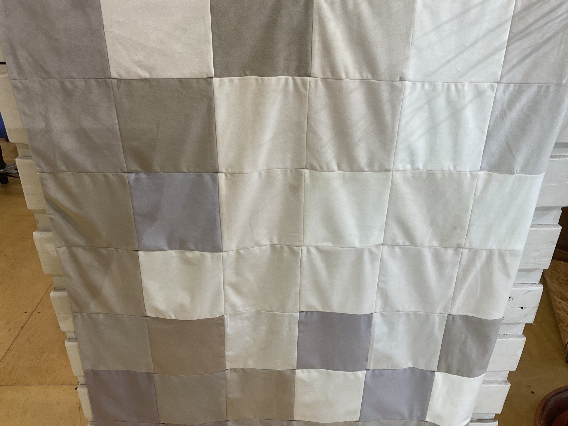 Blanket of checkered fabric panels on a wooden floor