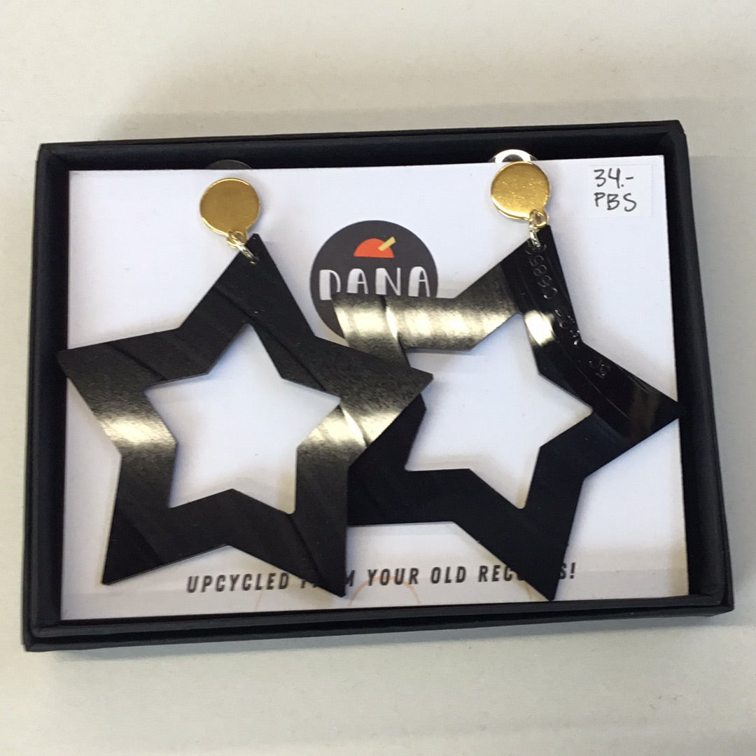 A pair of large black star-shaped earrings with gold studs, presented in a box with a brand tag.