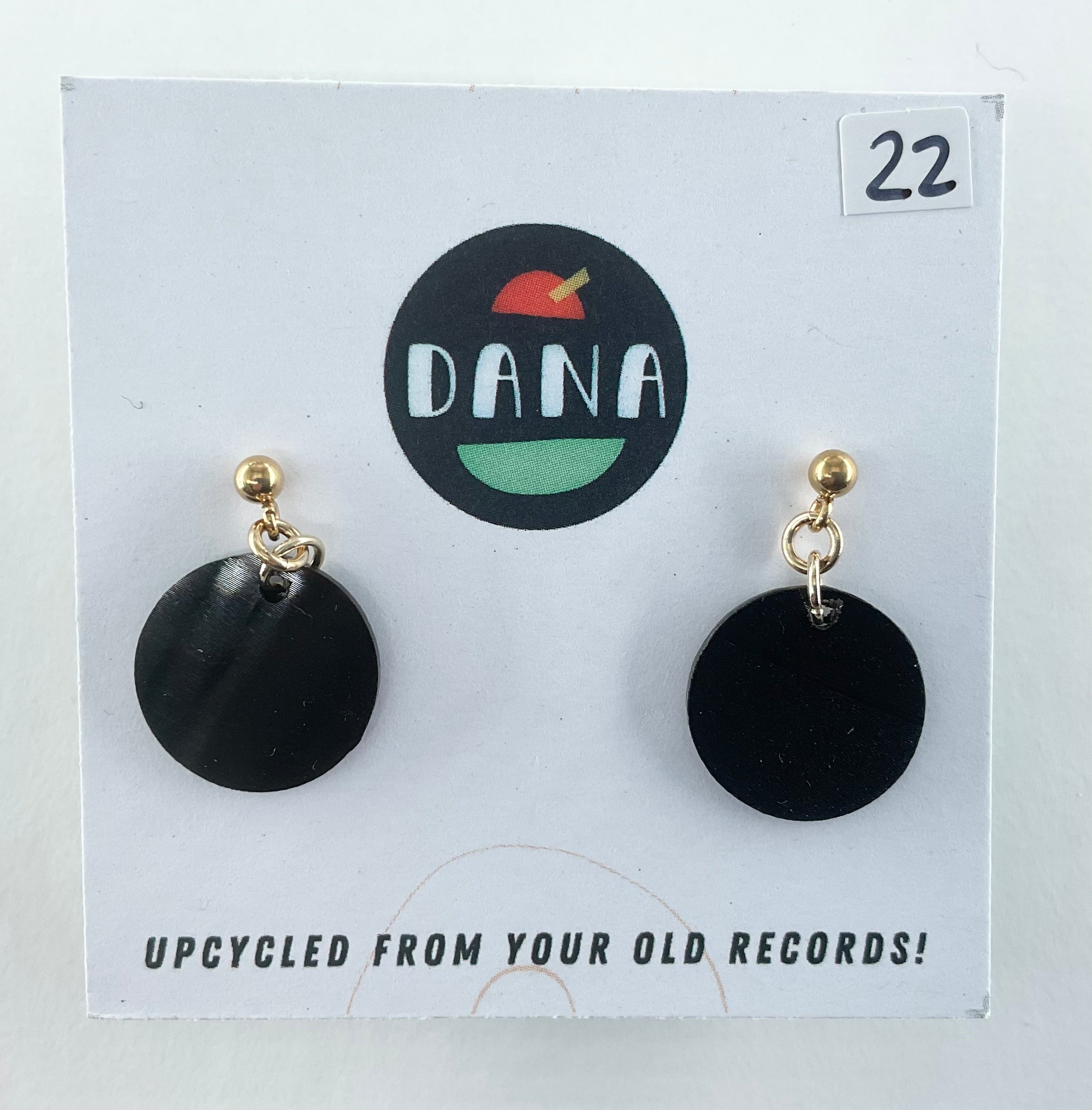 Black circular earrings on a Dana branded card with text about upcycling from old records.
