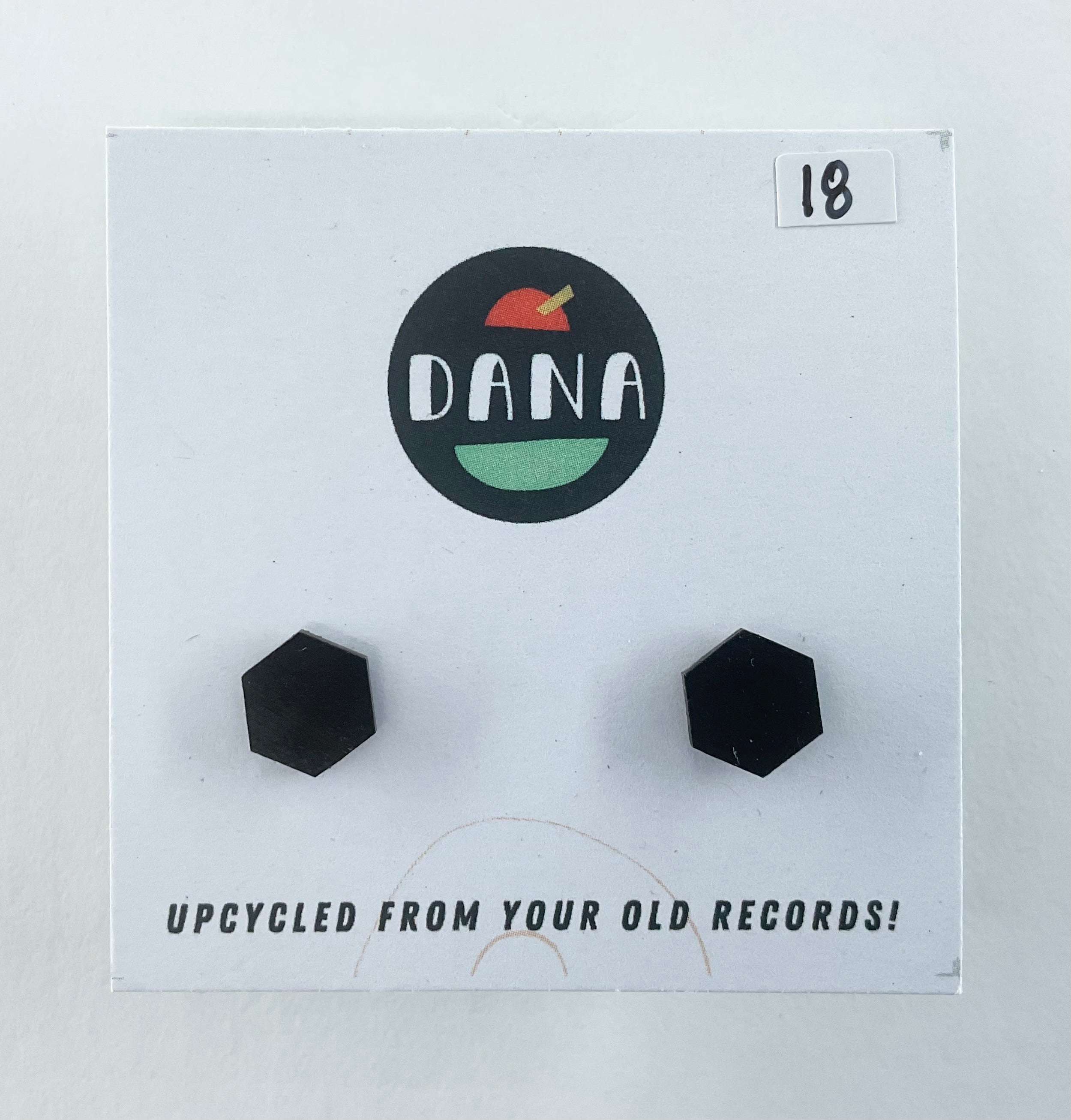 Black hexagonal earrings on a Dana branded card with text about upcycling from records.