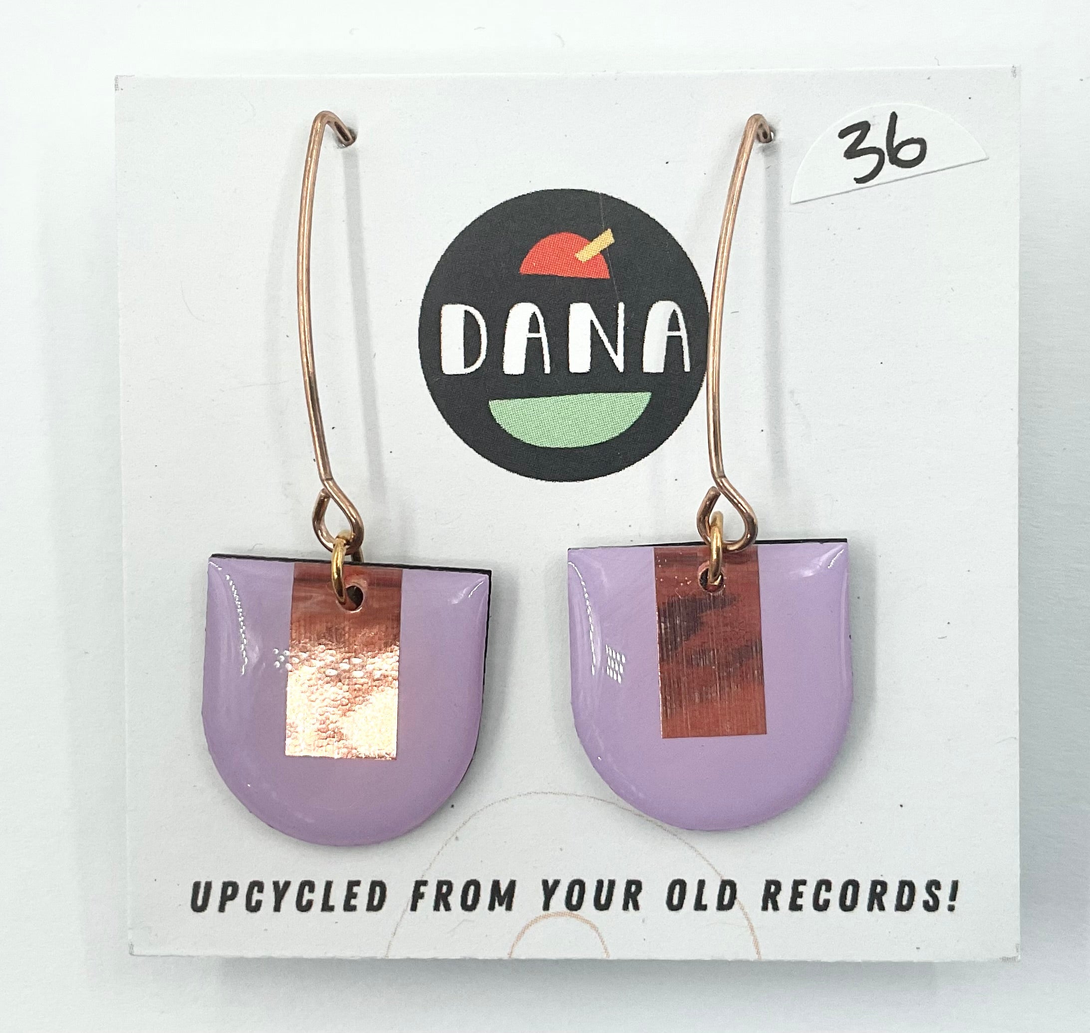 A pair of purple earrings with metallic details, labeled 'DANA' on a card that reads 'UPCYCLED FROM YOUR OLD RECORDS!'.