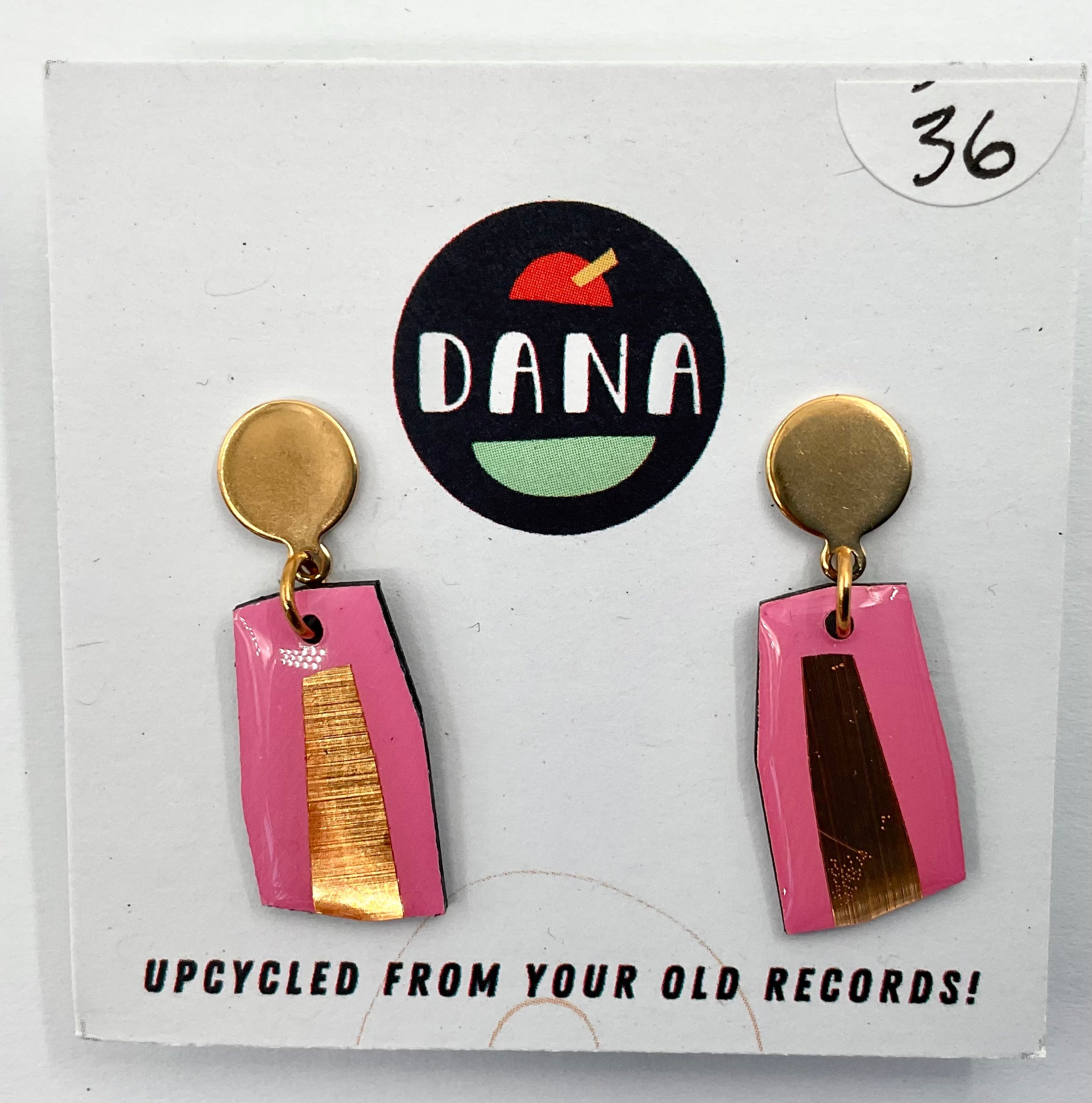 A pair of pink and metallic detailed earrings, with the brand name Dana featured in the background, indicating the earrings are upcycled from old records.