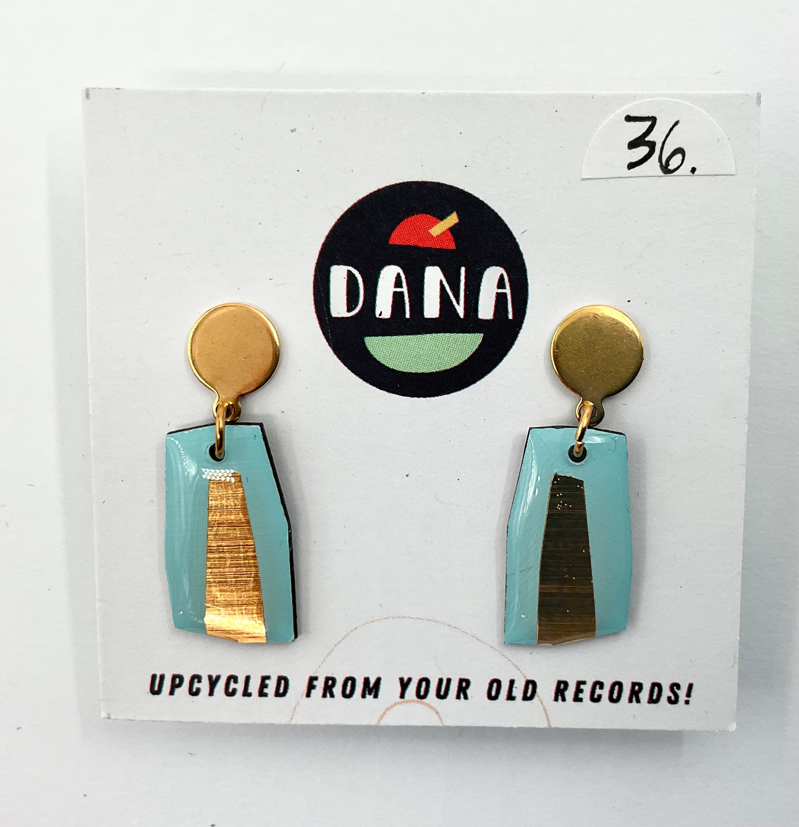 A pair of turquoise and metallic detailed earrings, displayed on a card with the brand name Dana.
