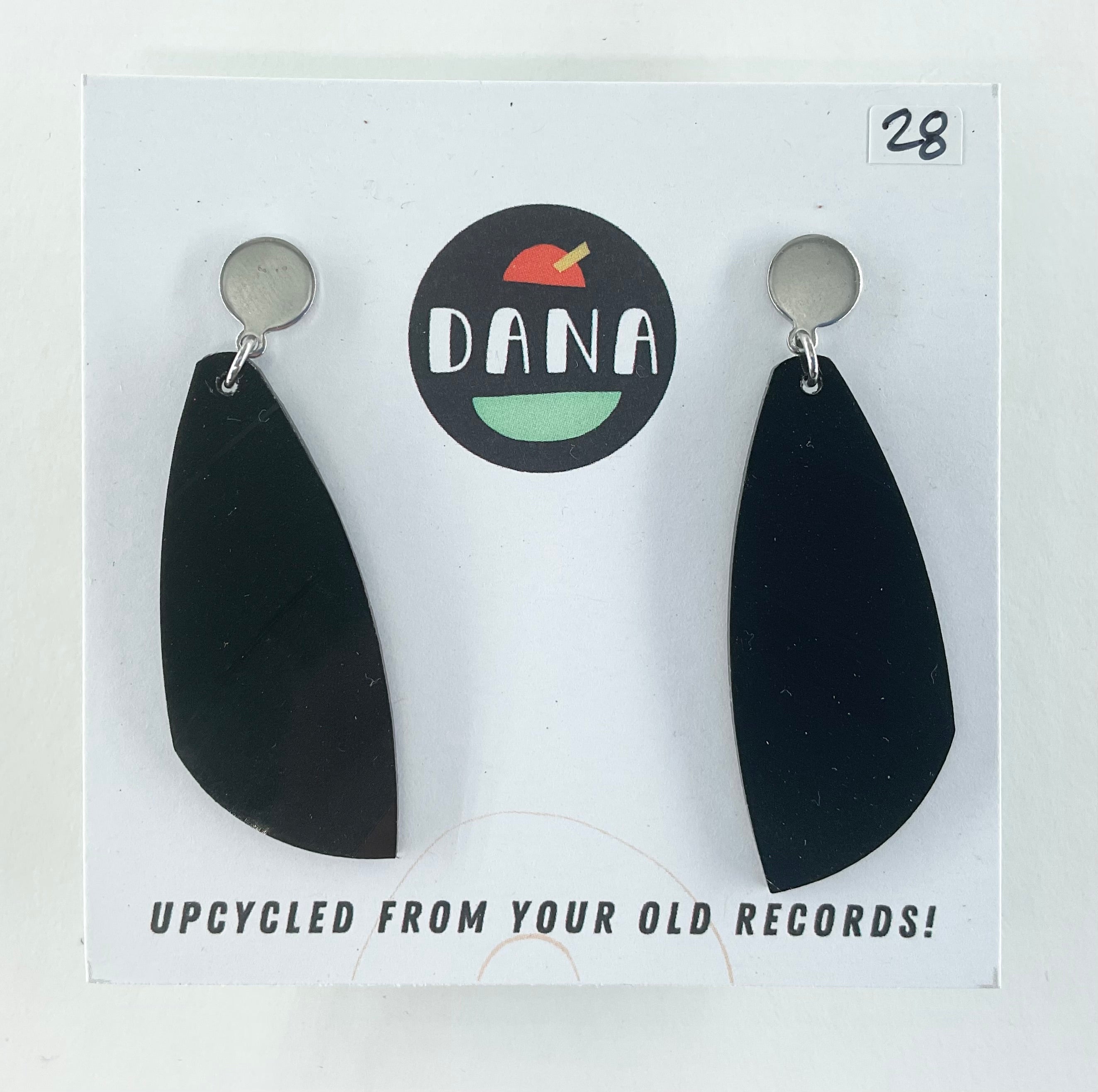 Black earrings on a white card with 'DANA' branding and text about upcycling from old records.