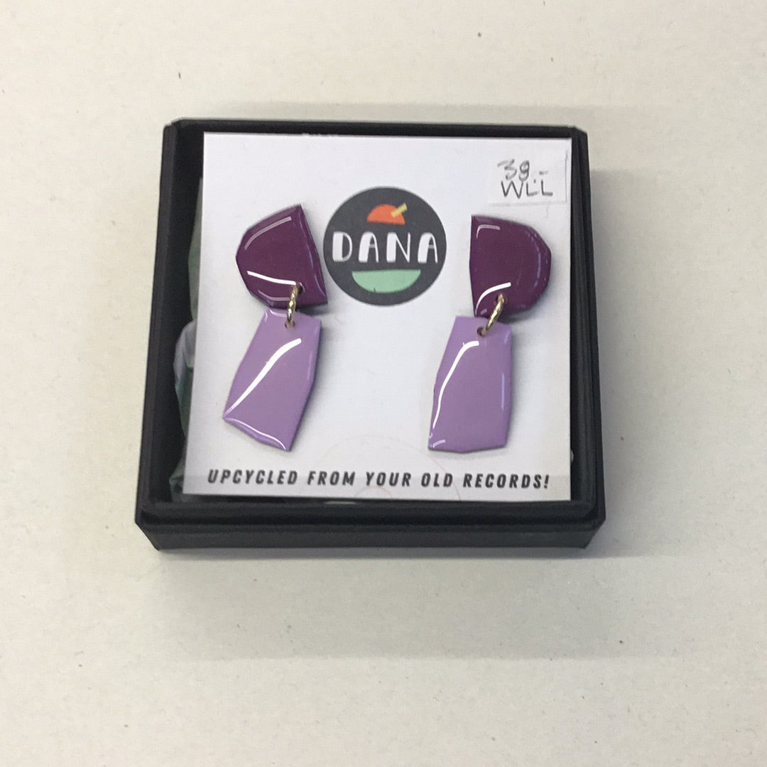 A pair of purple and lilac earrings made from upcycled vinyl records, presented in a black box with the brand name 'DANA' on it.