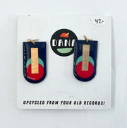 A pair of navy blue, red, turquoise, and gold earrings, displayed on a card with the brand name Dana.