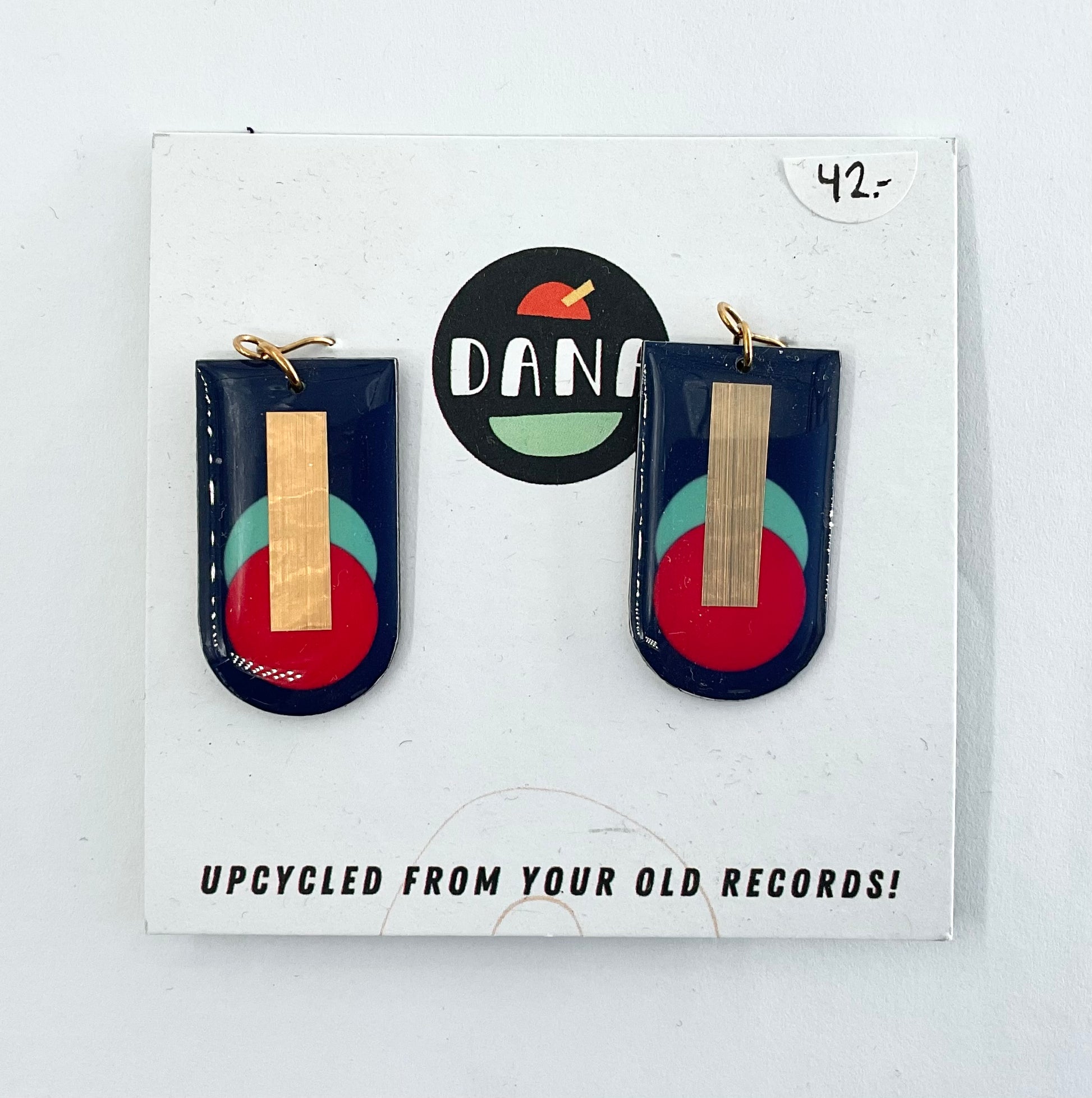 A pair of navy blue, red, turquoise, and gold earrings, displayed on a card with the brand name Dana.