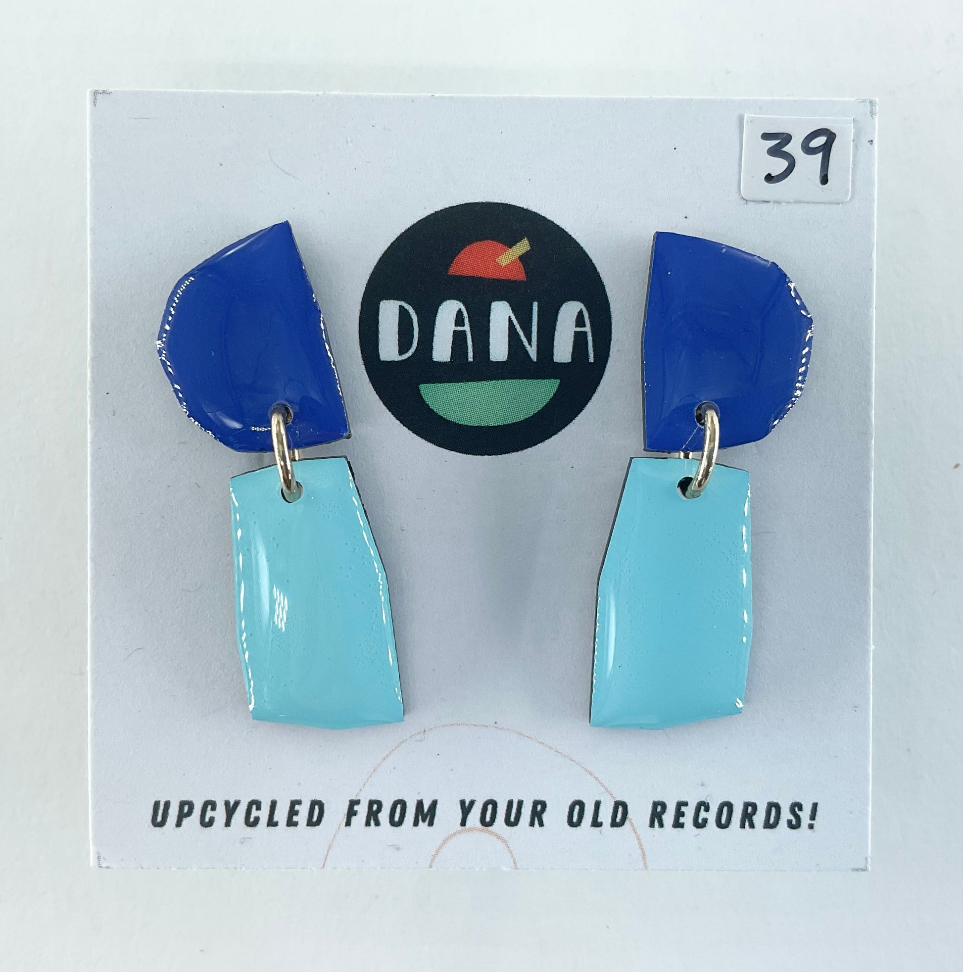 Blue and turquoise earrings on a card with 'DANA' branding and text about upcycling from old records.