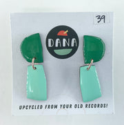 Green and teal earrings on a card with 'DANA' branding and text about upcycling from old records.