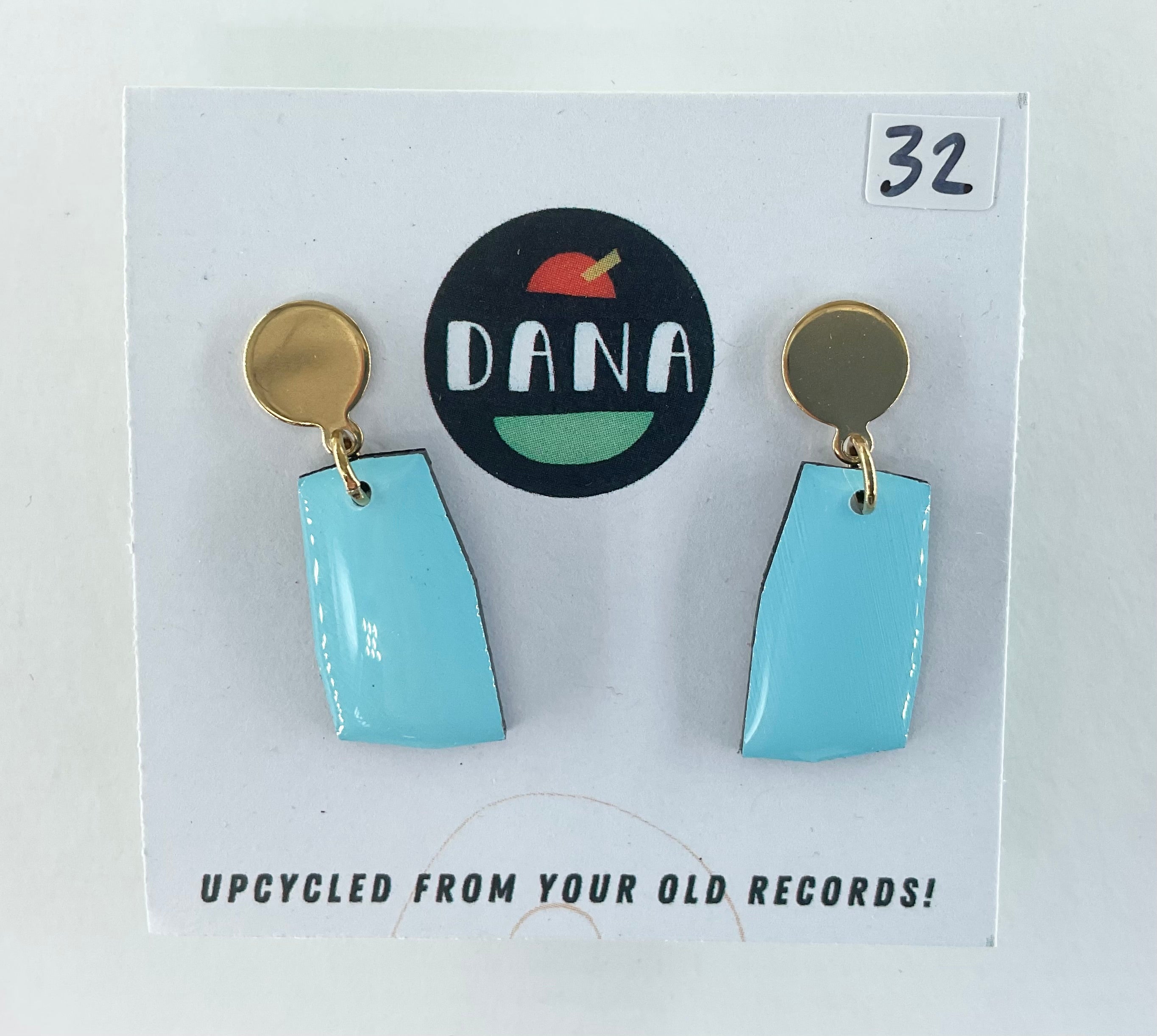 Pair of blue earrings on a card with 'DANA' branding and text about upcycling from old records.