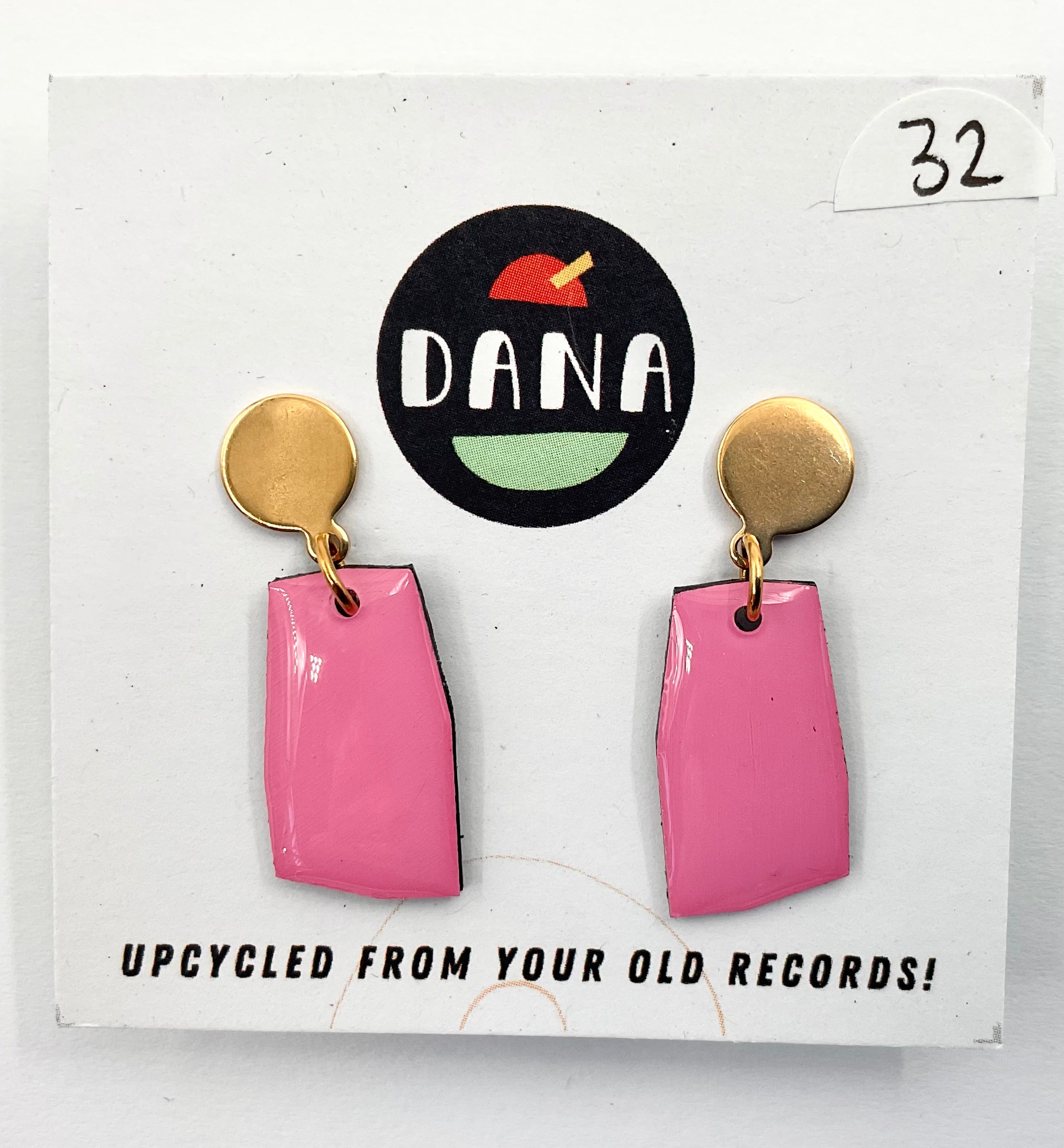 A pair of pink earrings with metallic details, displayed on a card with the Dana Jewellery brand logo and text 'UPCYCLED FROM YOUR OLD RECORDS!'.