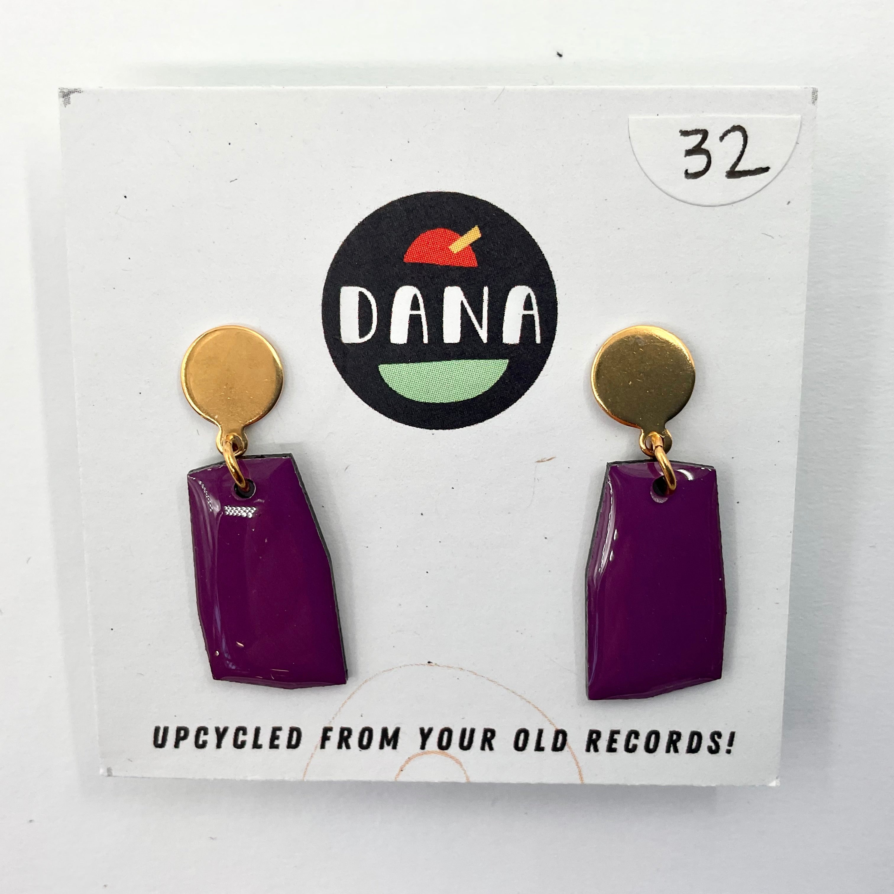 A pair of purple earrings with metallic details, labeled 'DANA' on a card that reads 'UPCYCLED FROM YOUR OLD RECORDS!'