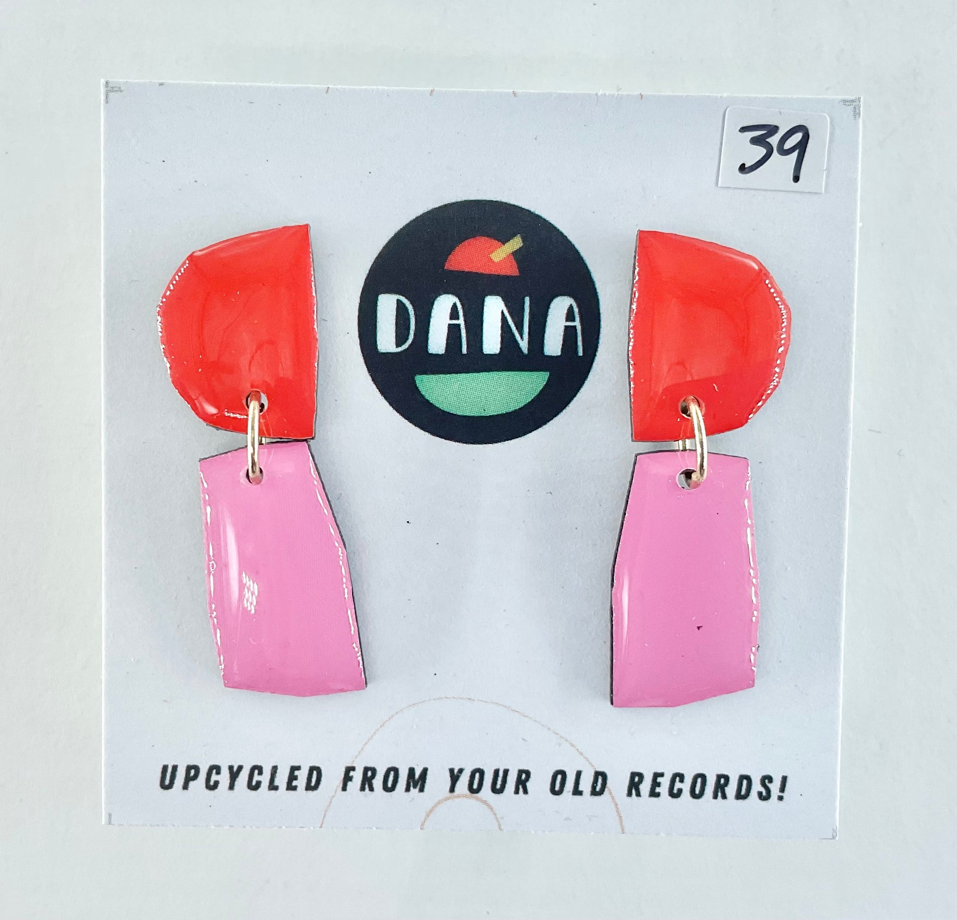 Colorful earrings on a card with 'DANA' branding and text about upcycling from old records.