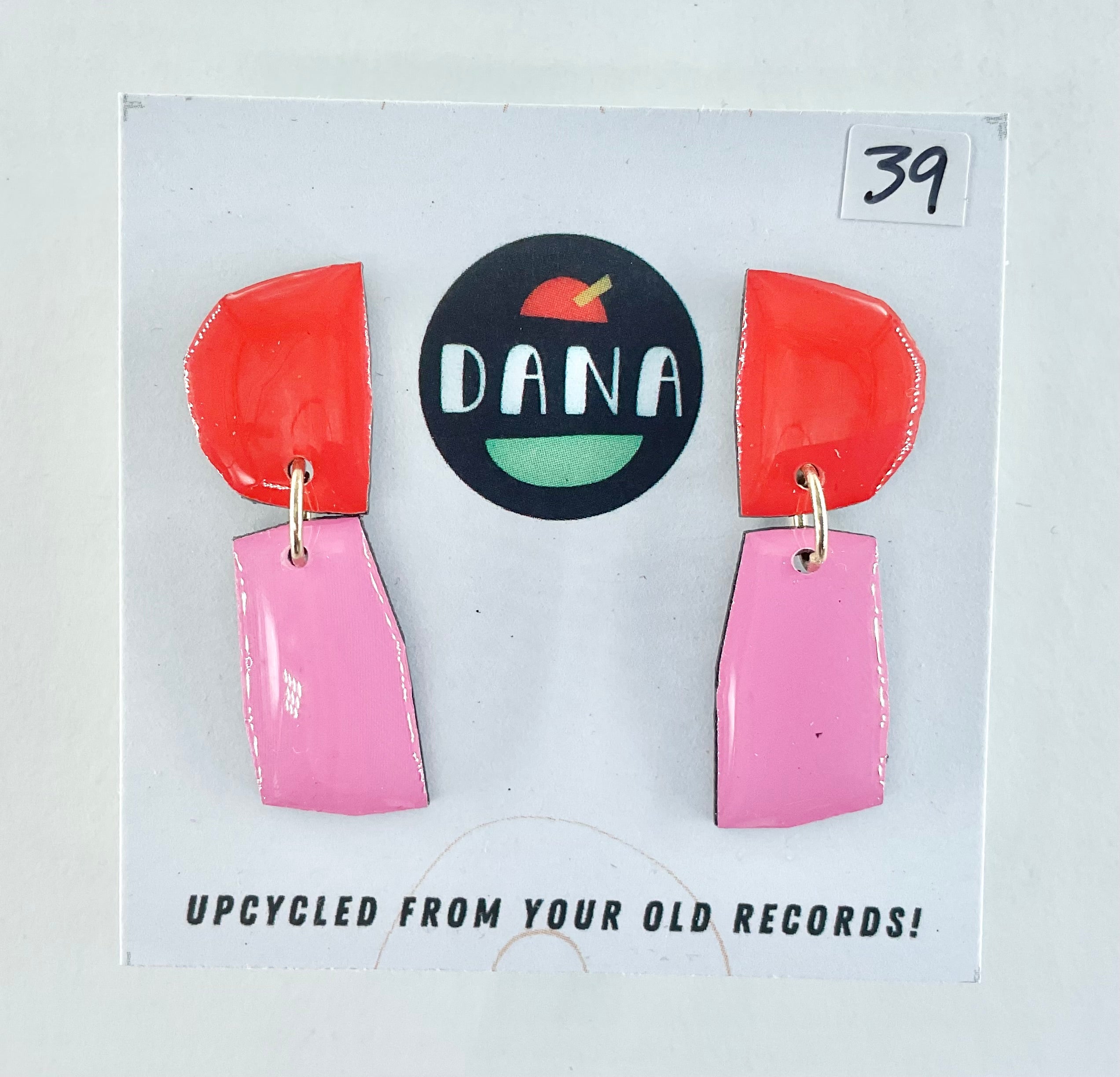 Colorful earrings on a card with 'DANA' branding and text about upcycling from old records.