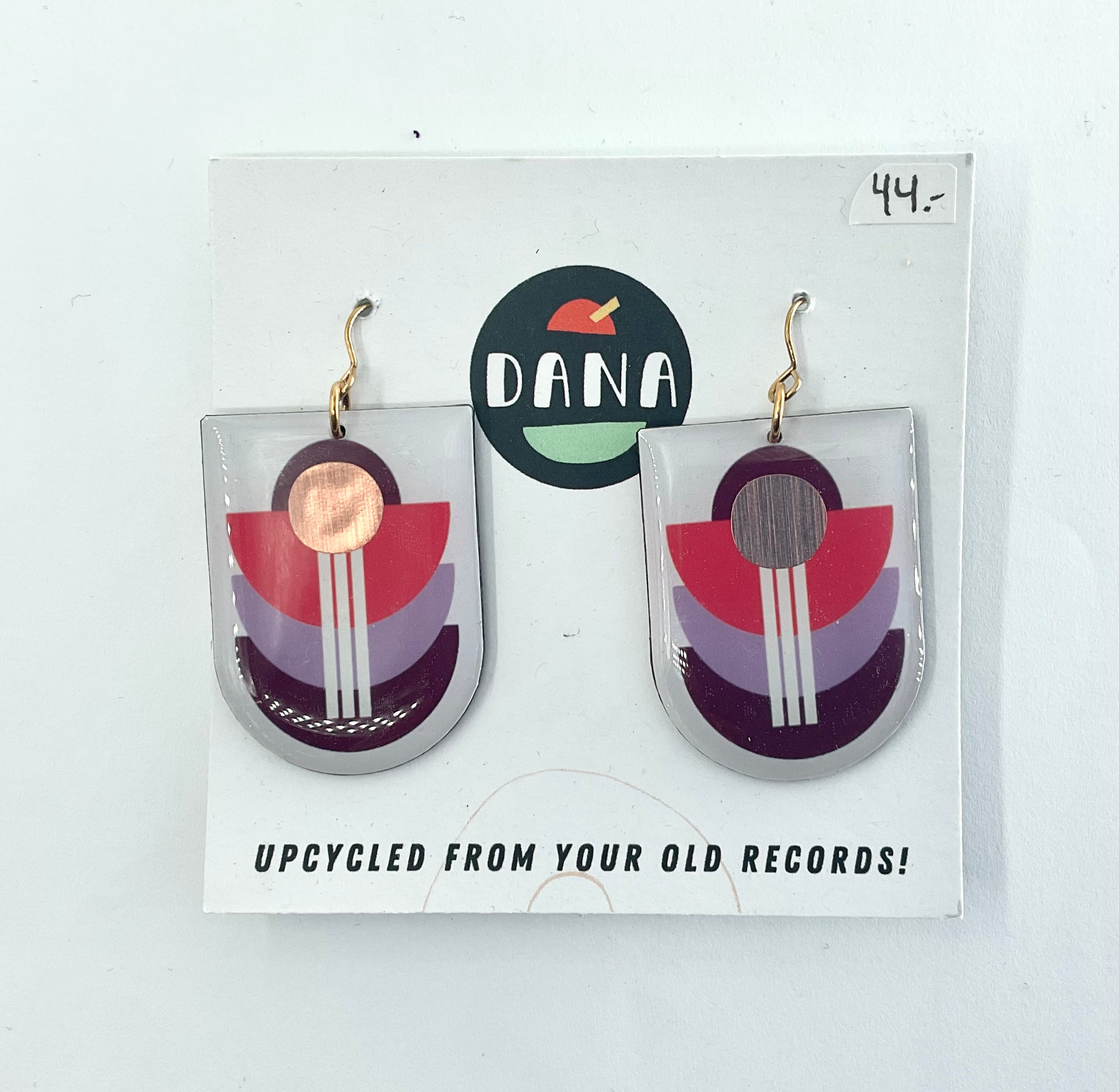 A pair of bronze multicolored earrings made from upcycled vinyl records, displayed on a white card with the brand name 'dana' at the top.