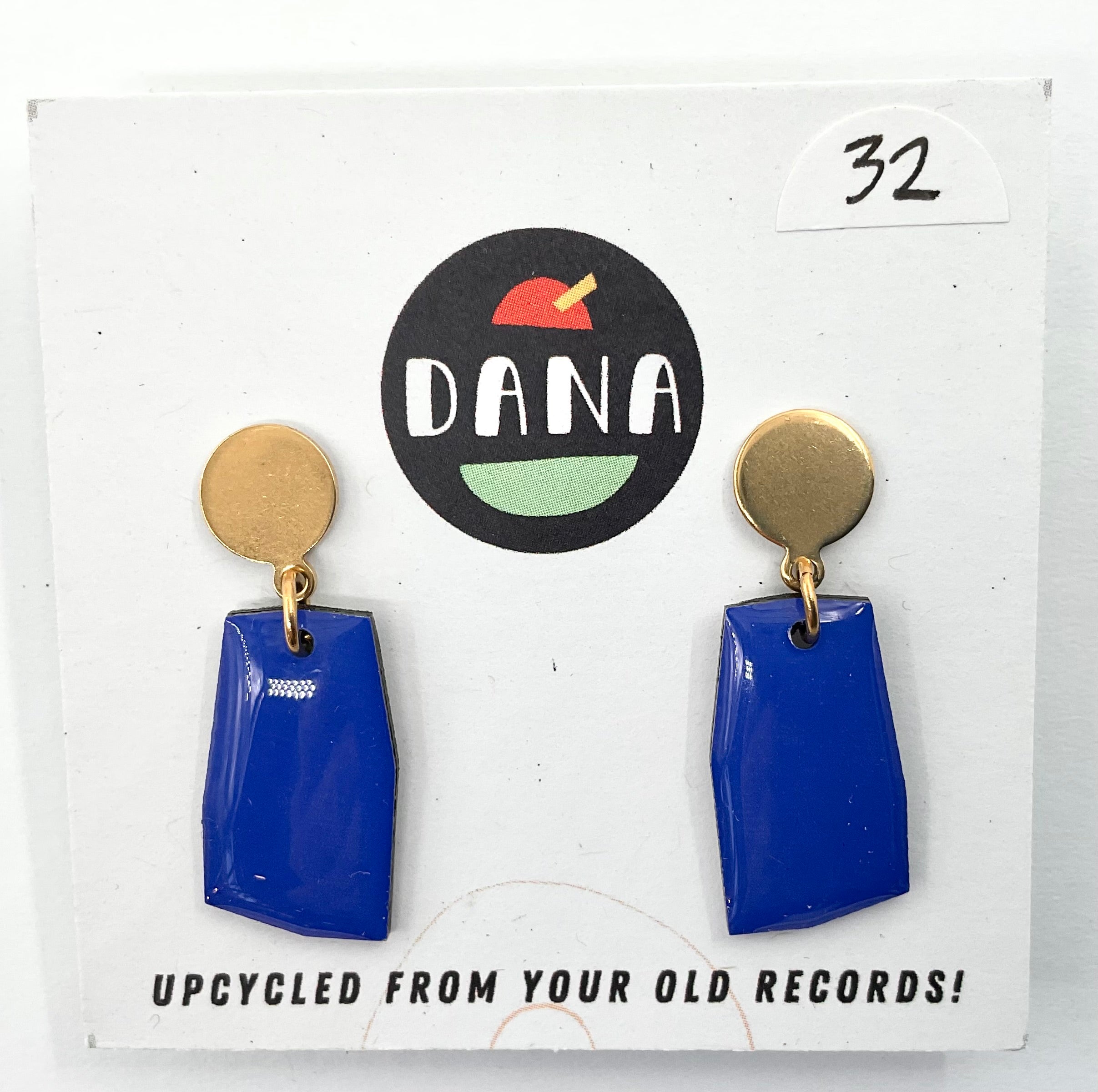 A pair of blue earrings with metallic details, displayed on a card with the Dana brand logo and text 'UPCYCLED FROM YOUR OLD RECORDS!'.