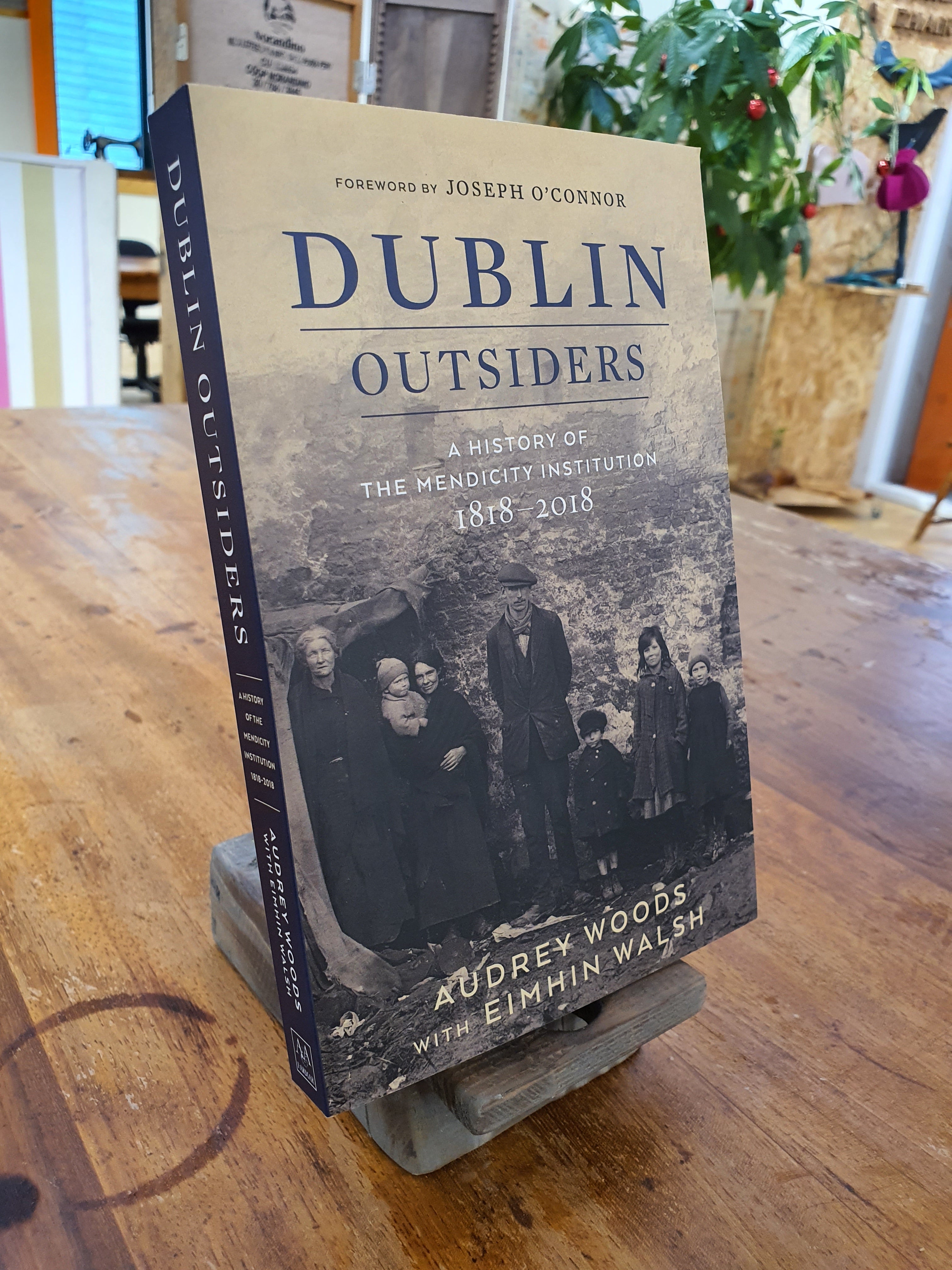 A book titled 'Dublin Outsiders - A History of the Mendicity Institution 1818-2018' displayed on a wooden surface with a foreword by J.C.