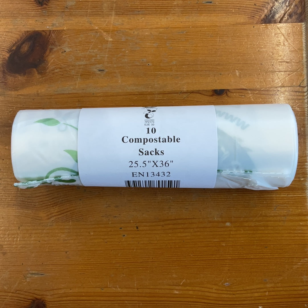 A roll of compostable bin liners with a label indicating 10 sacks, size 25.5 x 43 cm, EN13432 XXL 4321, on a wooden surface.