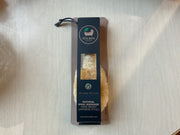 A natural sisal massage hand brush packaged in a brown paper bag with a black label featuring the brand name and product details.