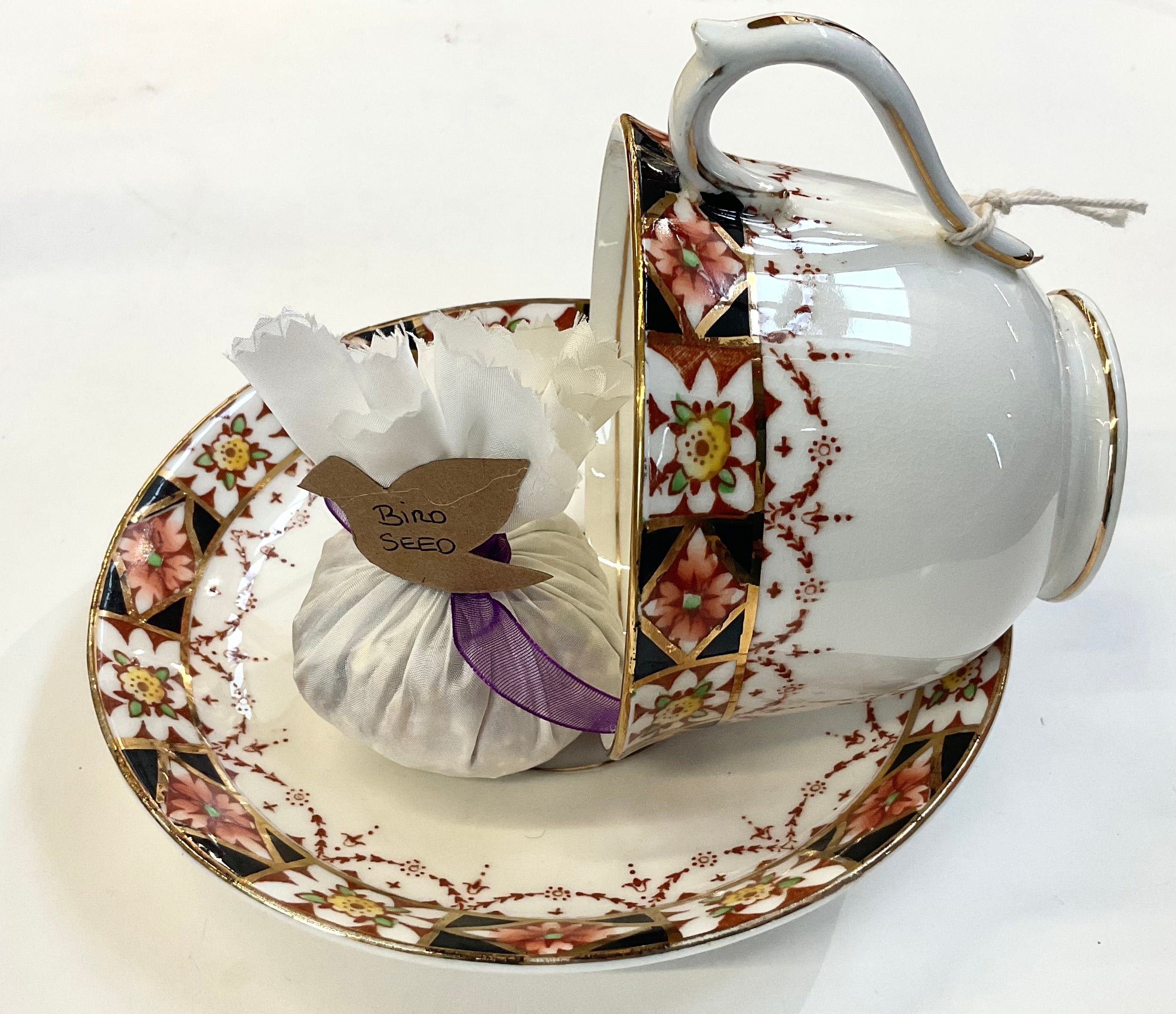Bird feeder made from a teacup and saucer with floral patterns on a white background