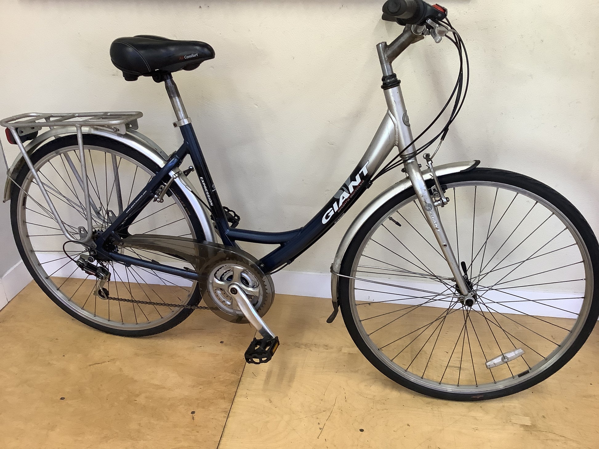 Bicycle with 'Giant' branding on a wooden floor against a white wall