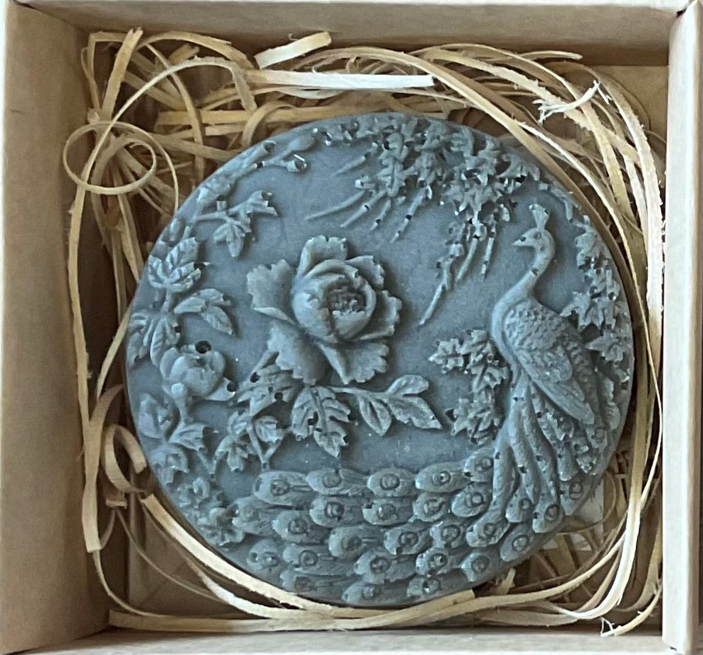 Decorative stone with peacock and floral design in a box with straw