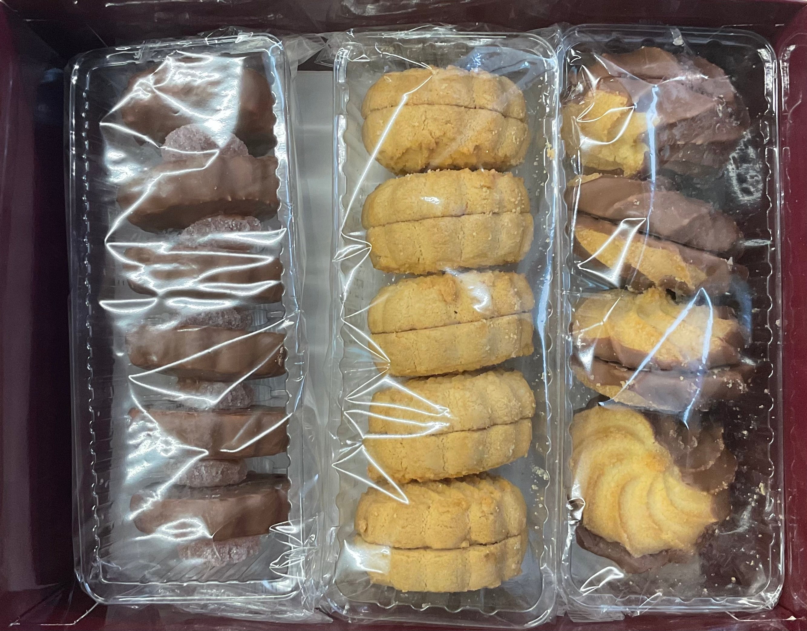 Assorted cookies in clear plastic packaging on a dark surface