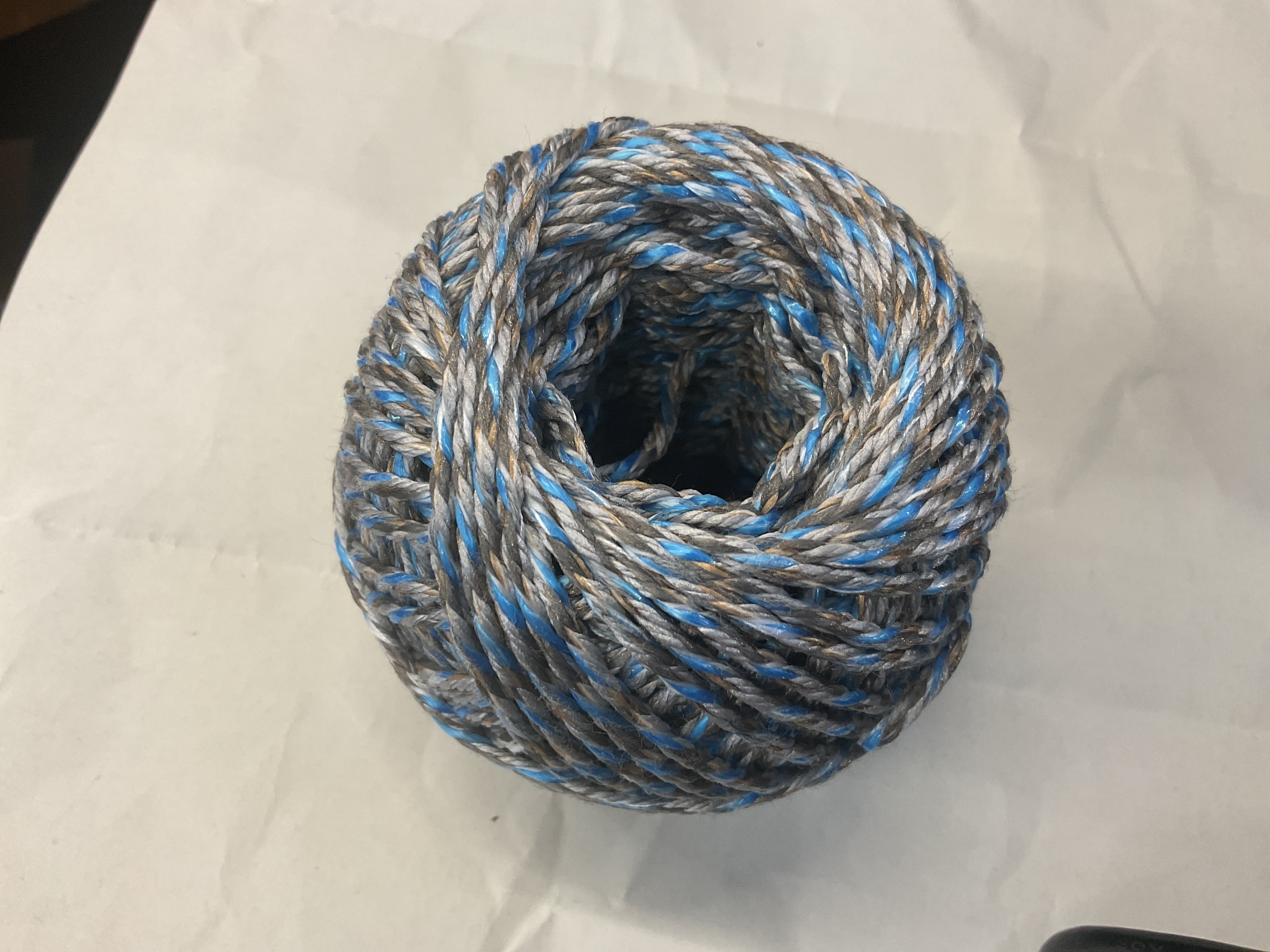 Coiled rope with blue and gray pattern on a white background