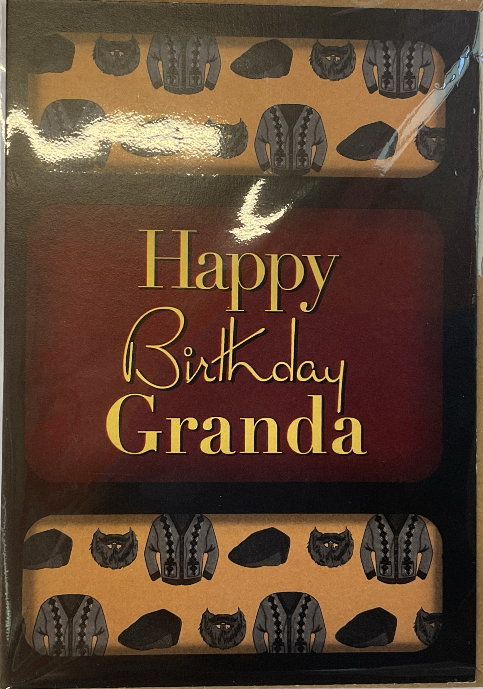 A birthday card with a dark background featuring text 'Happy Birthday Granda' in a prominent font, surrounded by a pattern of black clothes.