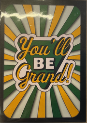 A greeting card with the phrase 'You'll Be Grand!' written in a stylized font, with green, white, and yellow background rays.