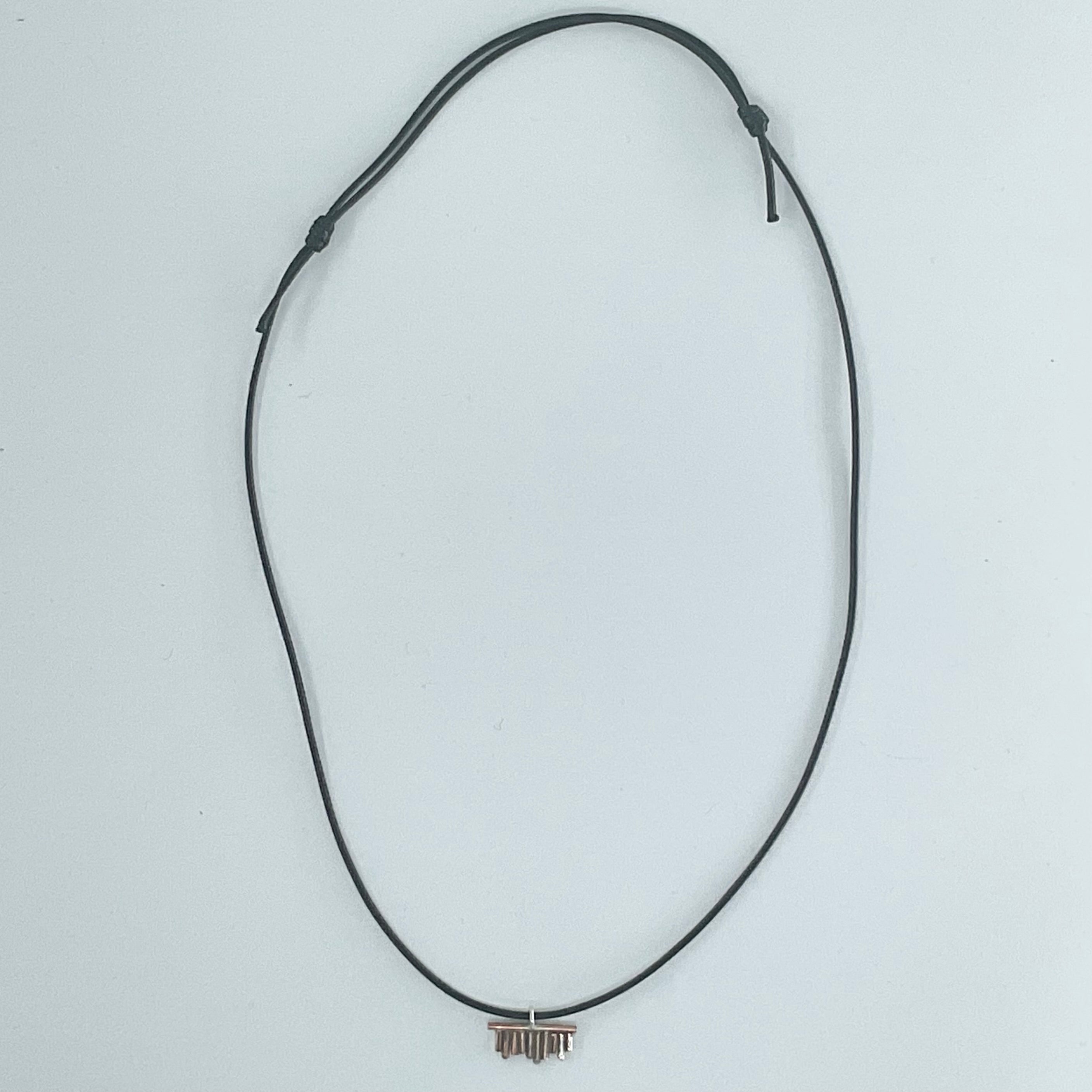 A black adjustable cord necklace with a small metallic bar pendant, displayed on a plain light gray background.