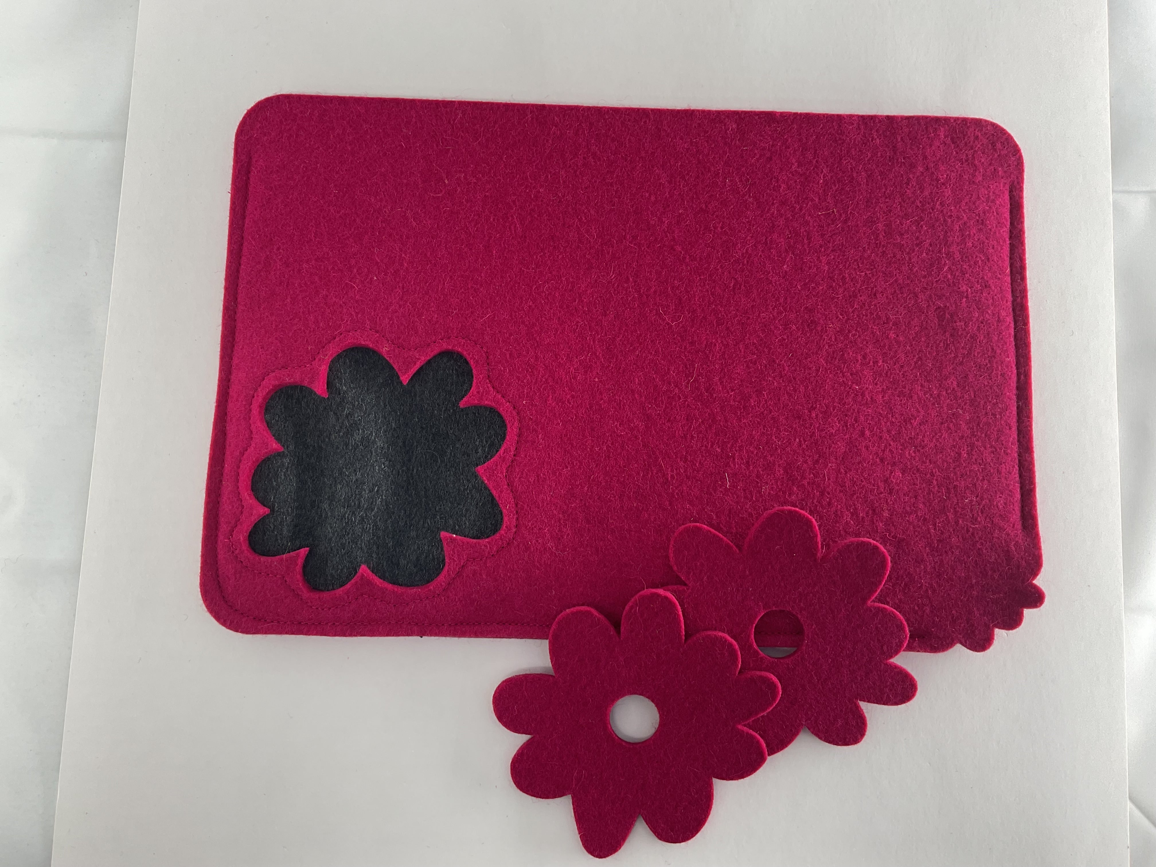 Pink tea cosy and coasters with black and pink flower designs on a white background