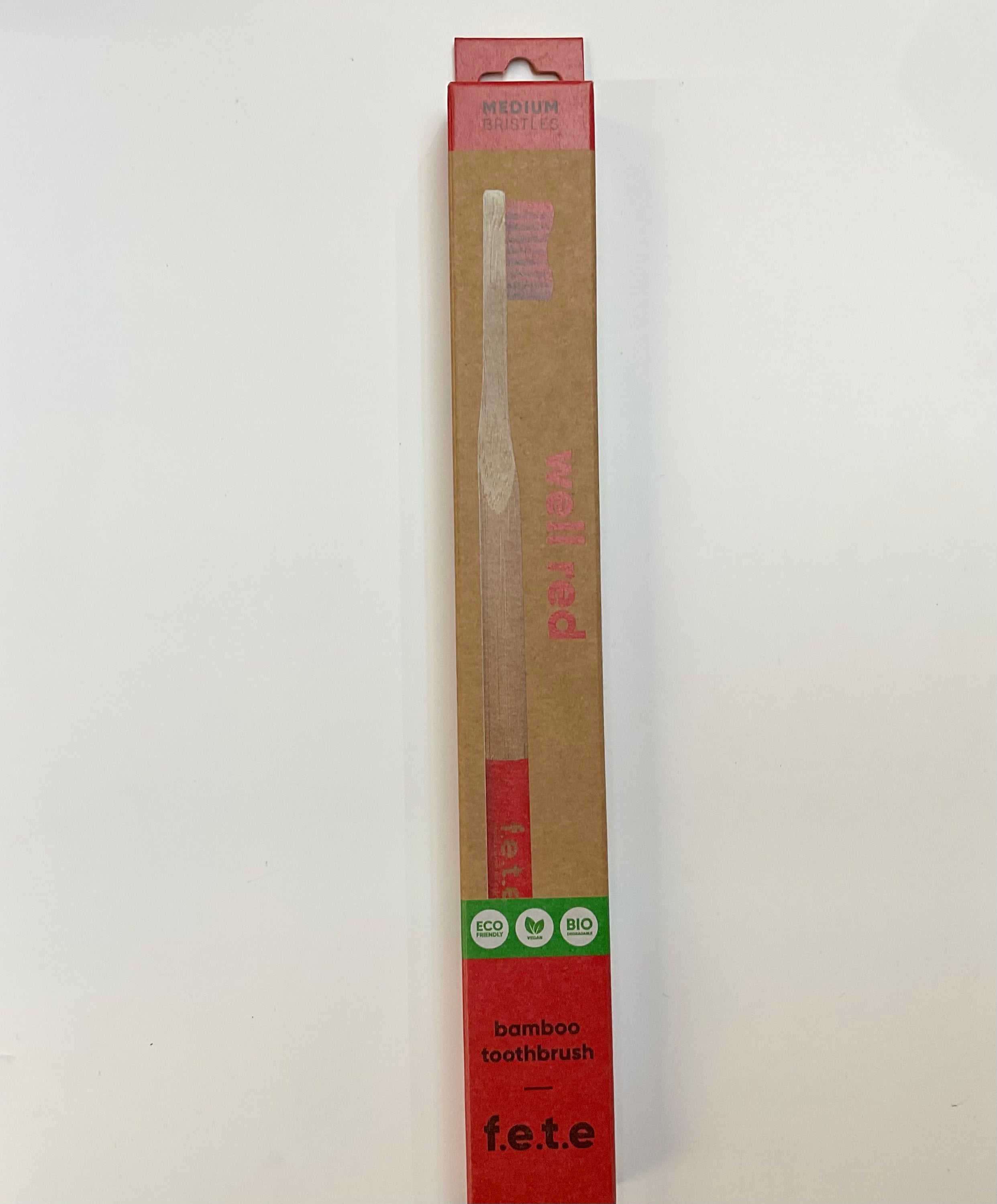A red and white Humble Brush toothbrush packaged in eco-friendly packaging with the brand name F.E.T.E visible on the box.