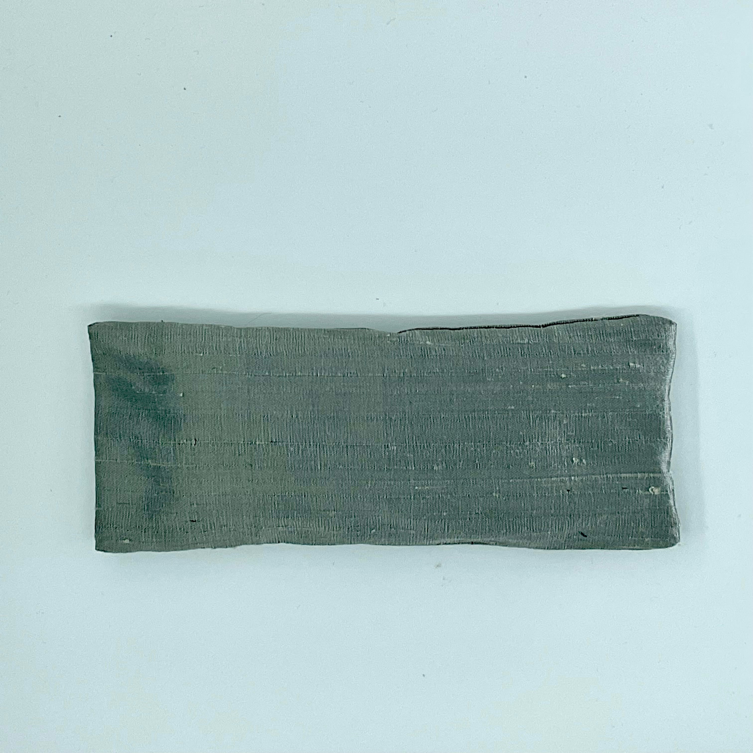 A gray silk eye mask laid flat on a white background.