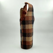 A recycled fabric wine holder with a checkered pattern, featuring a shoulder strap.