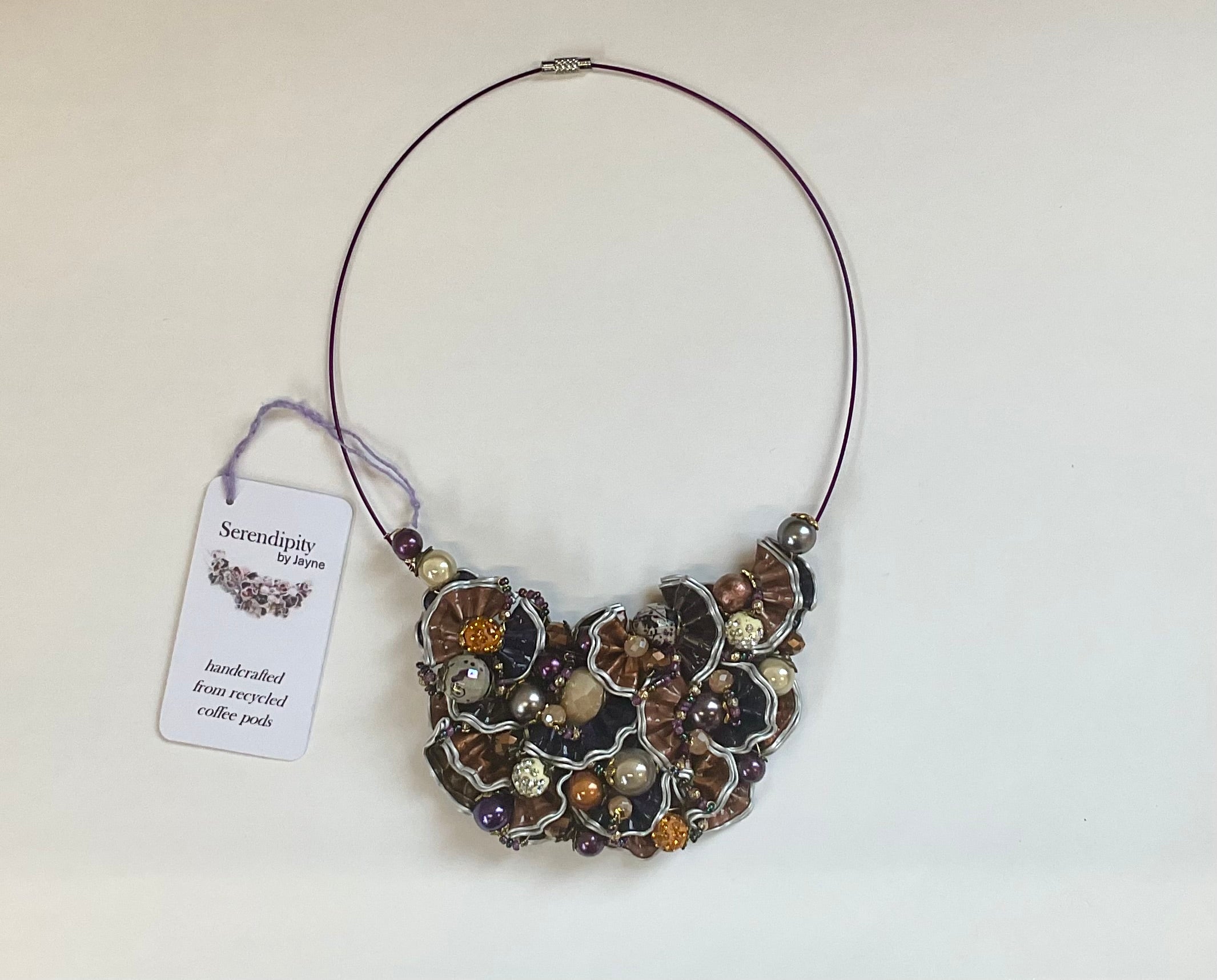 Necklace with intricate design and tag on a light background