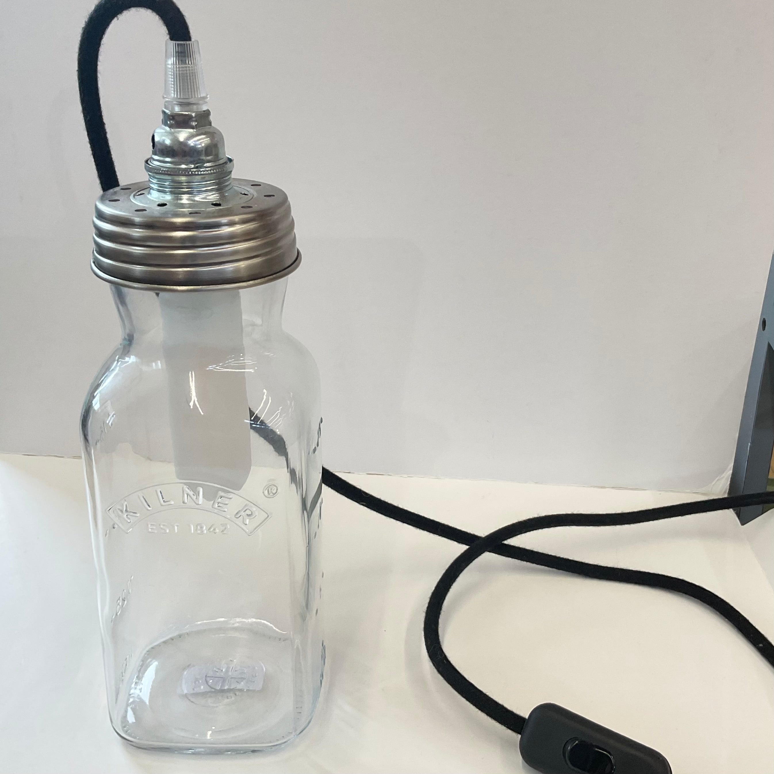 A clear glass mason jar bottle with a metal screw-top spout and a black cord, shown on a white surface against a white background.