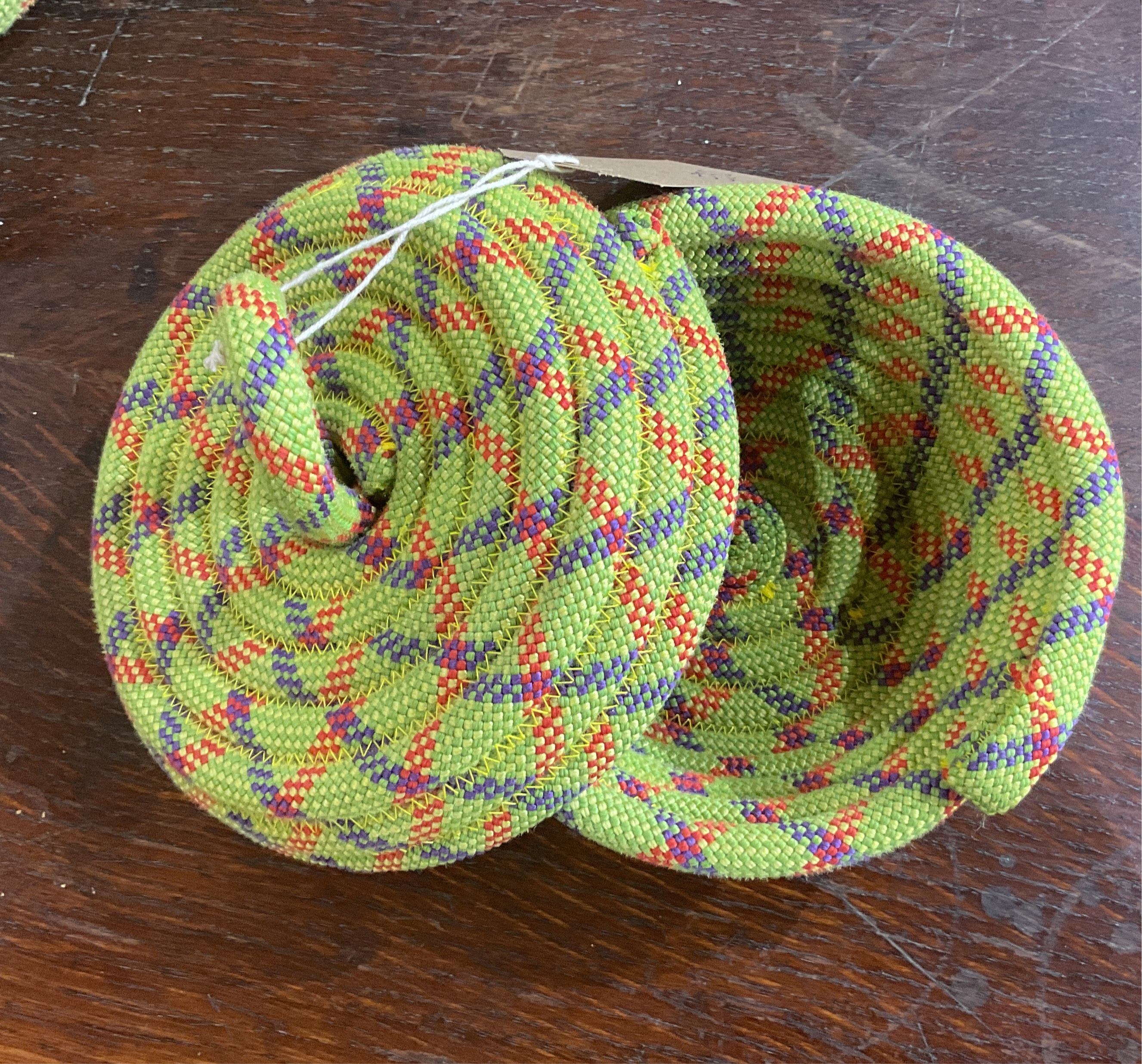 basket made from rope with a lid. rope is sewn with yellow thread, and woven together from blue, red, yellow and light green threads.
