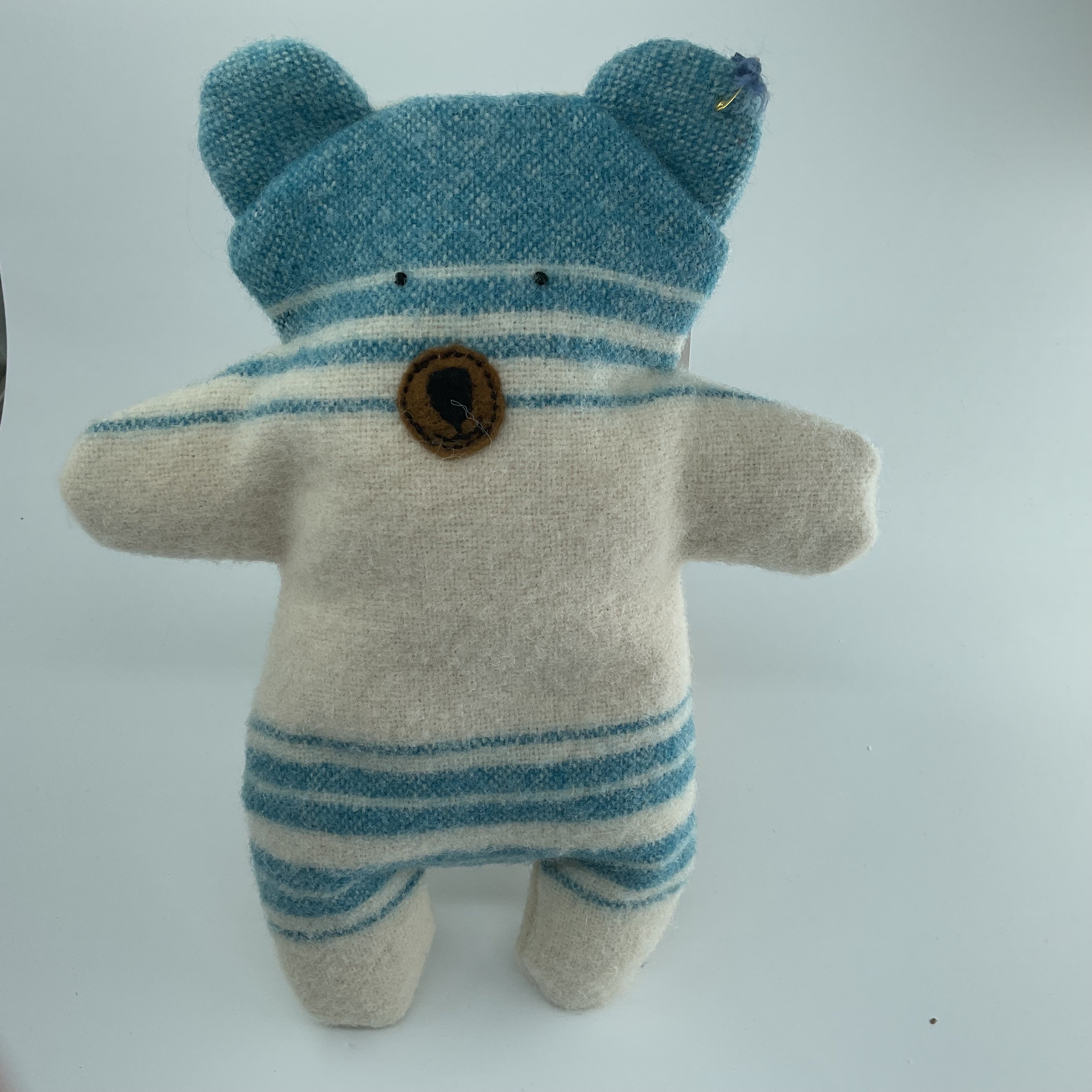 Stuffed toy bear with blue and white striped outfit on a light gray background